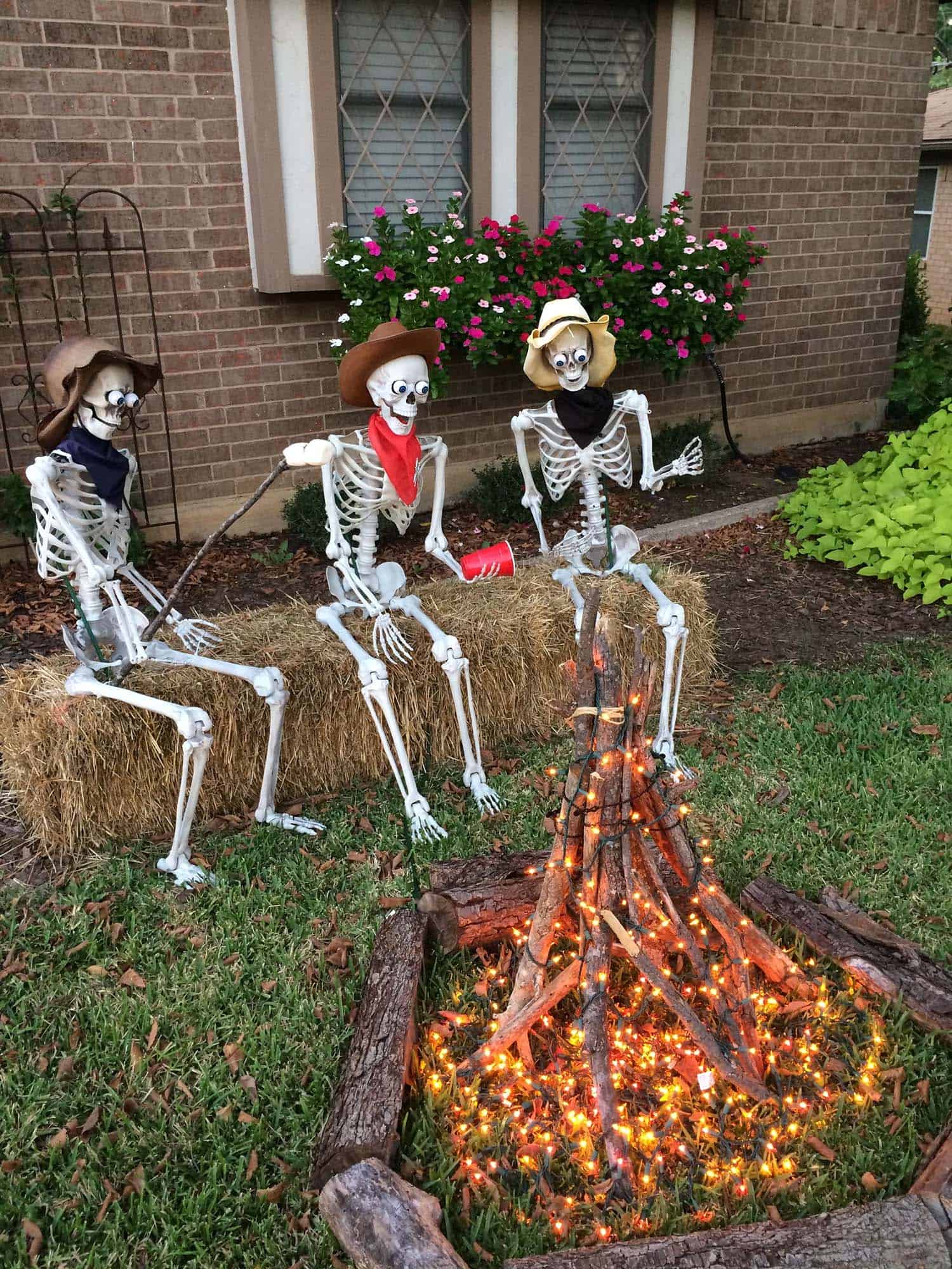 skeleton cowboys sitting around a faux campfire in the yard for Halloween