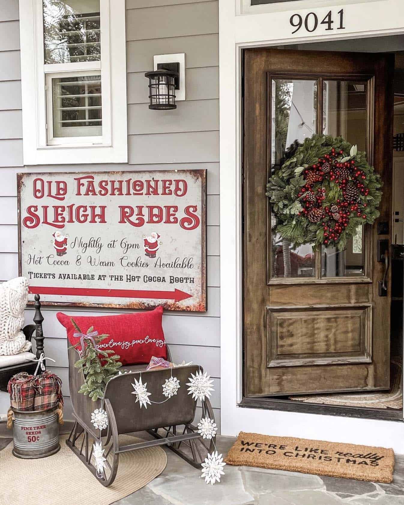 vintage style Christmas decor on the front porch with a sleigh, sign and wreath