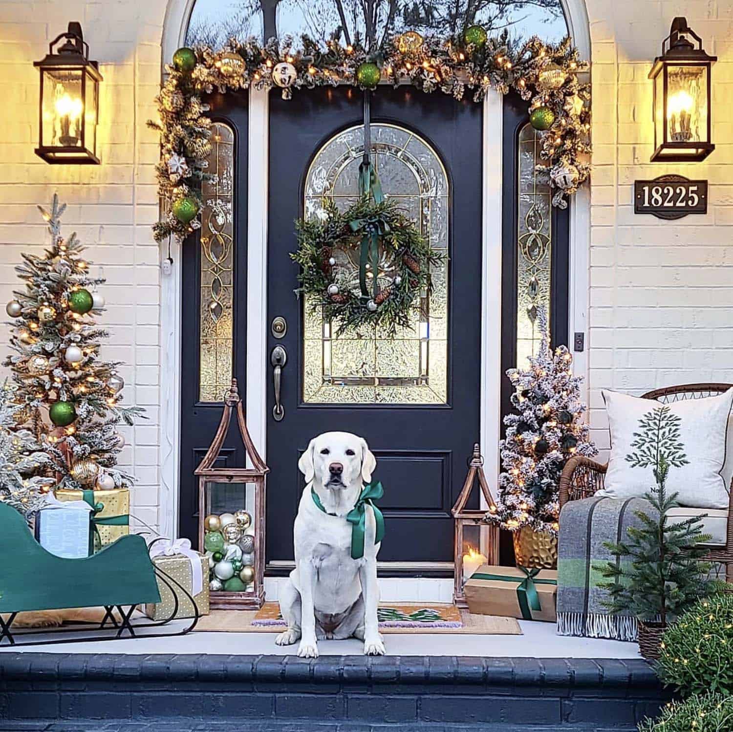 Christmas decorated front porch with garland, flocked trees and a sled