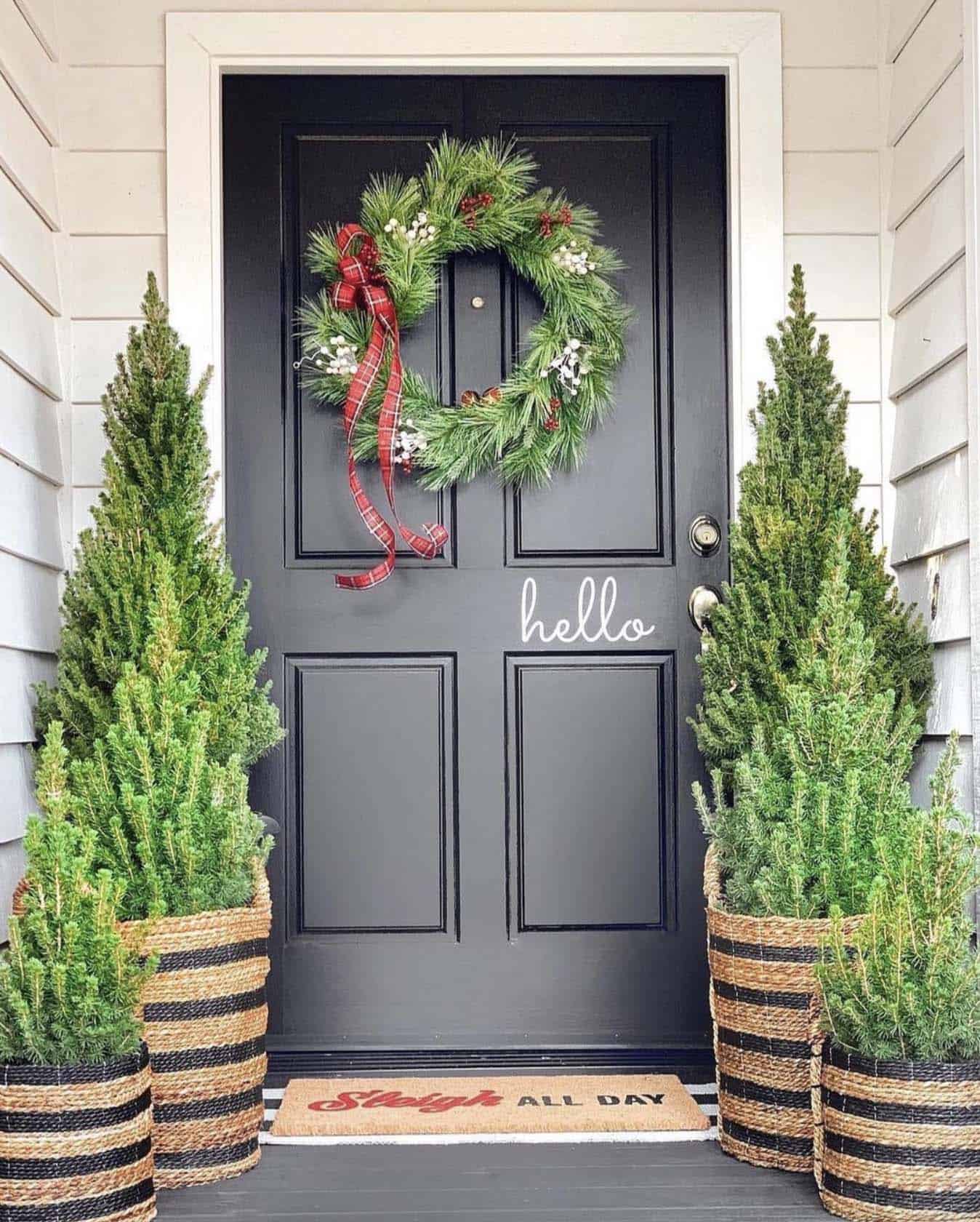 front door decorated with Alberta spruce trees and a Christmas wreath