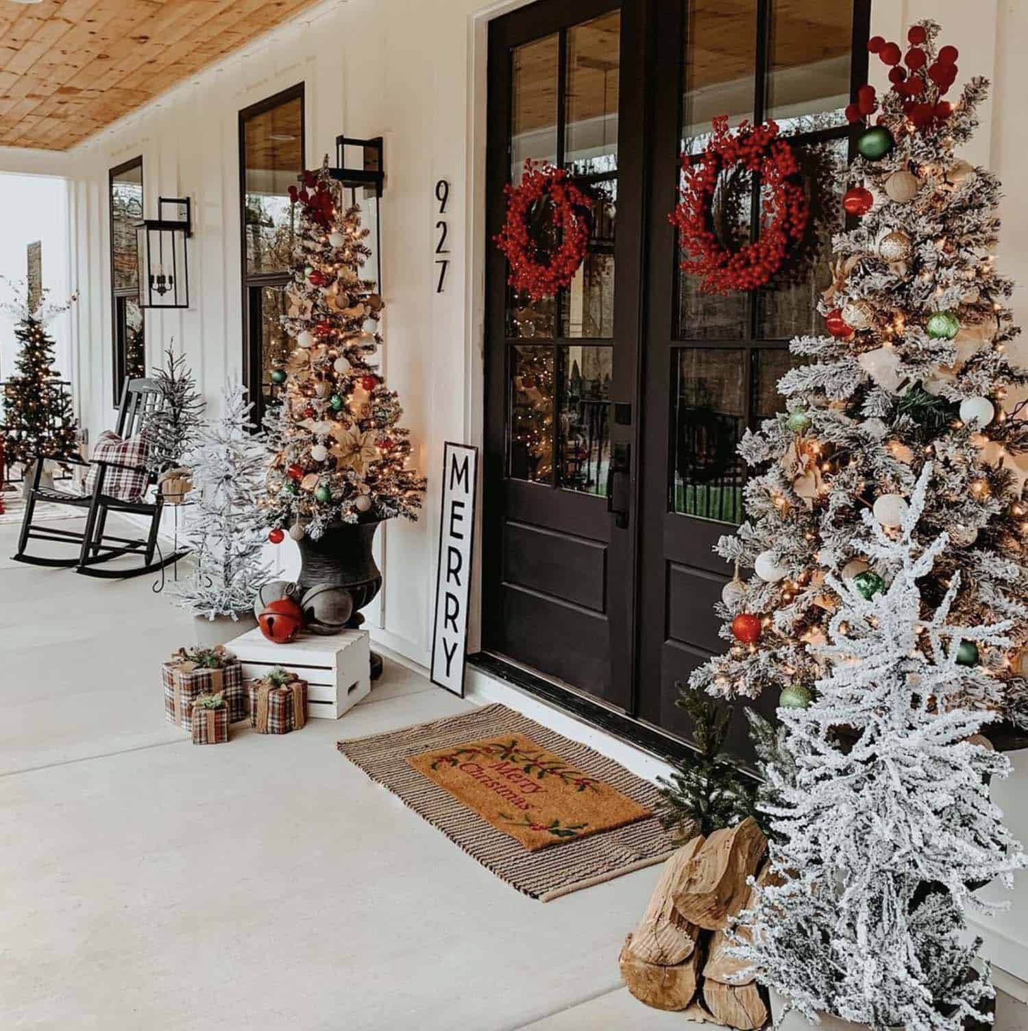farmhouse style Christmas porch with trees, wreaths, plaid presents and bells