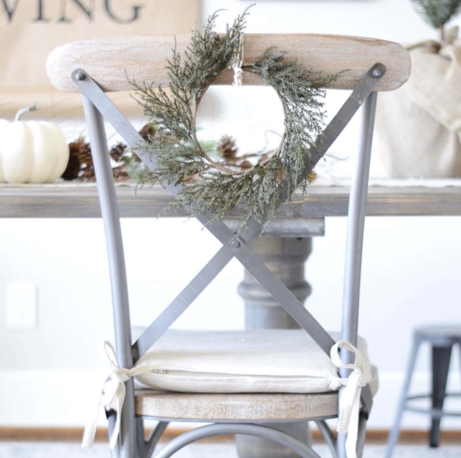cozy neutral thanksgiving table with a wreath on the chair back