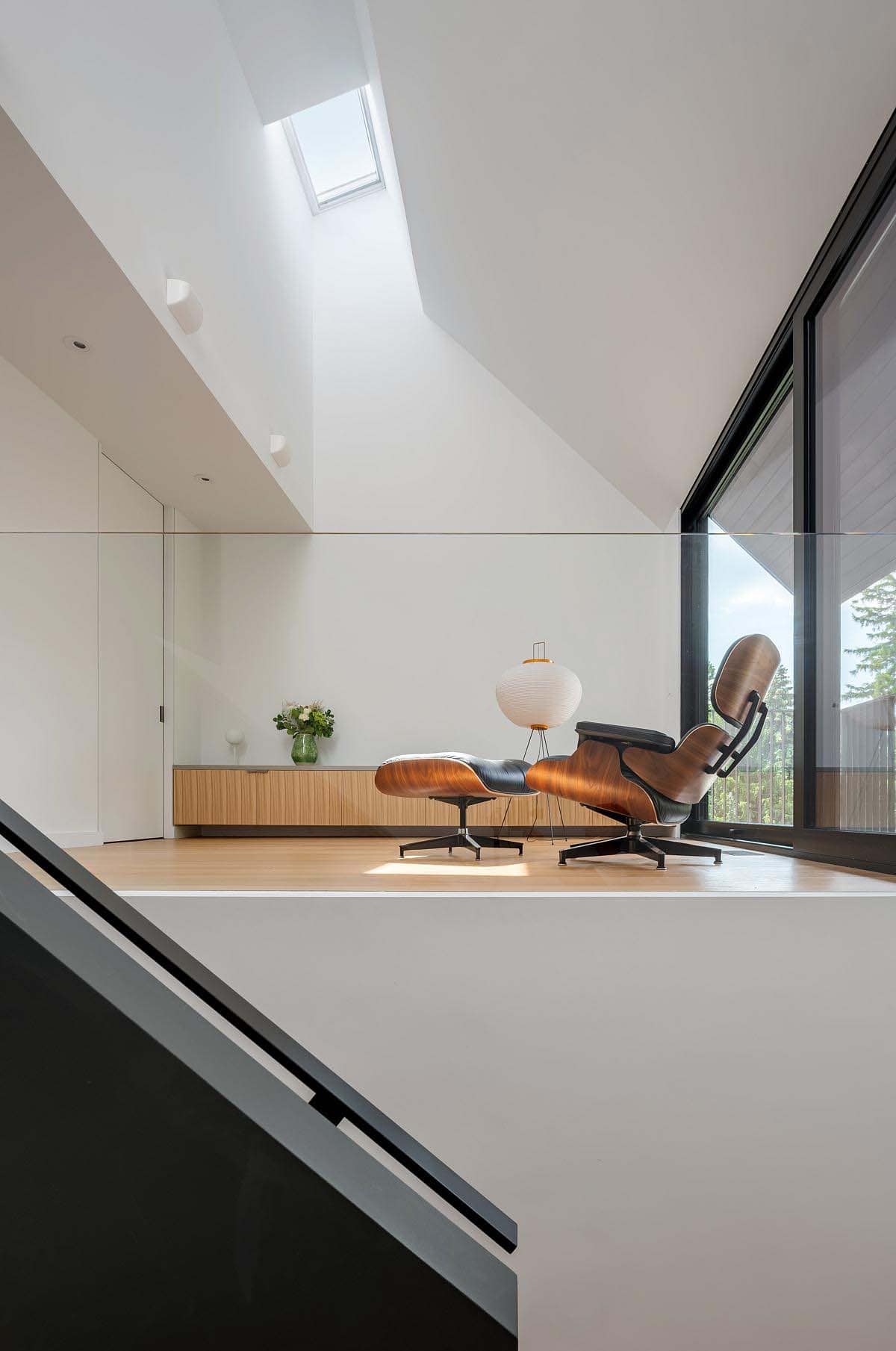 contemporary reading nook with an Eames chair and ottoman illuminated with a skylight and siding glass doors