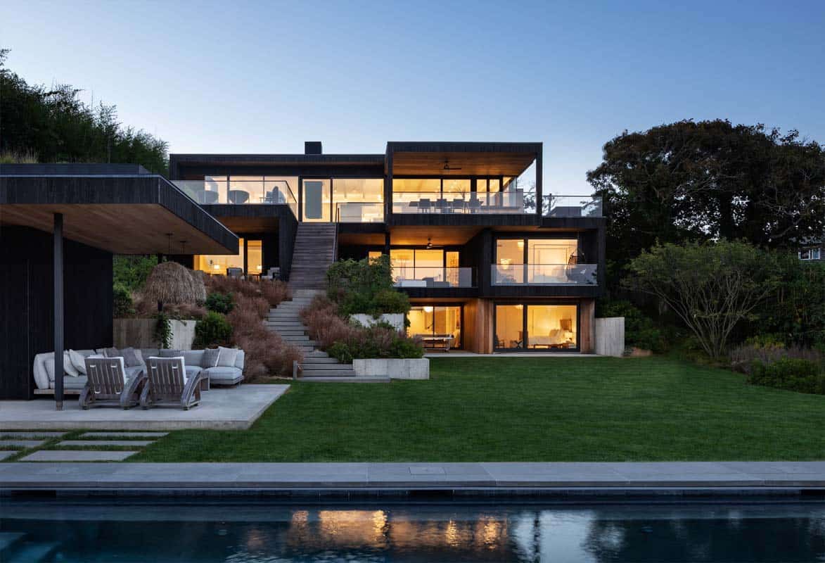 contemporary oceanside home exterior with a pool at dusk