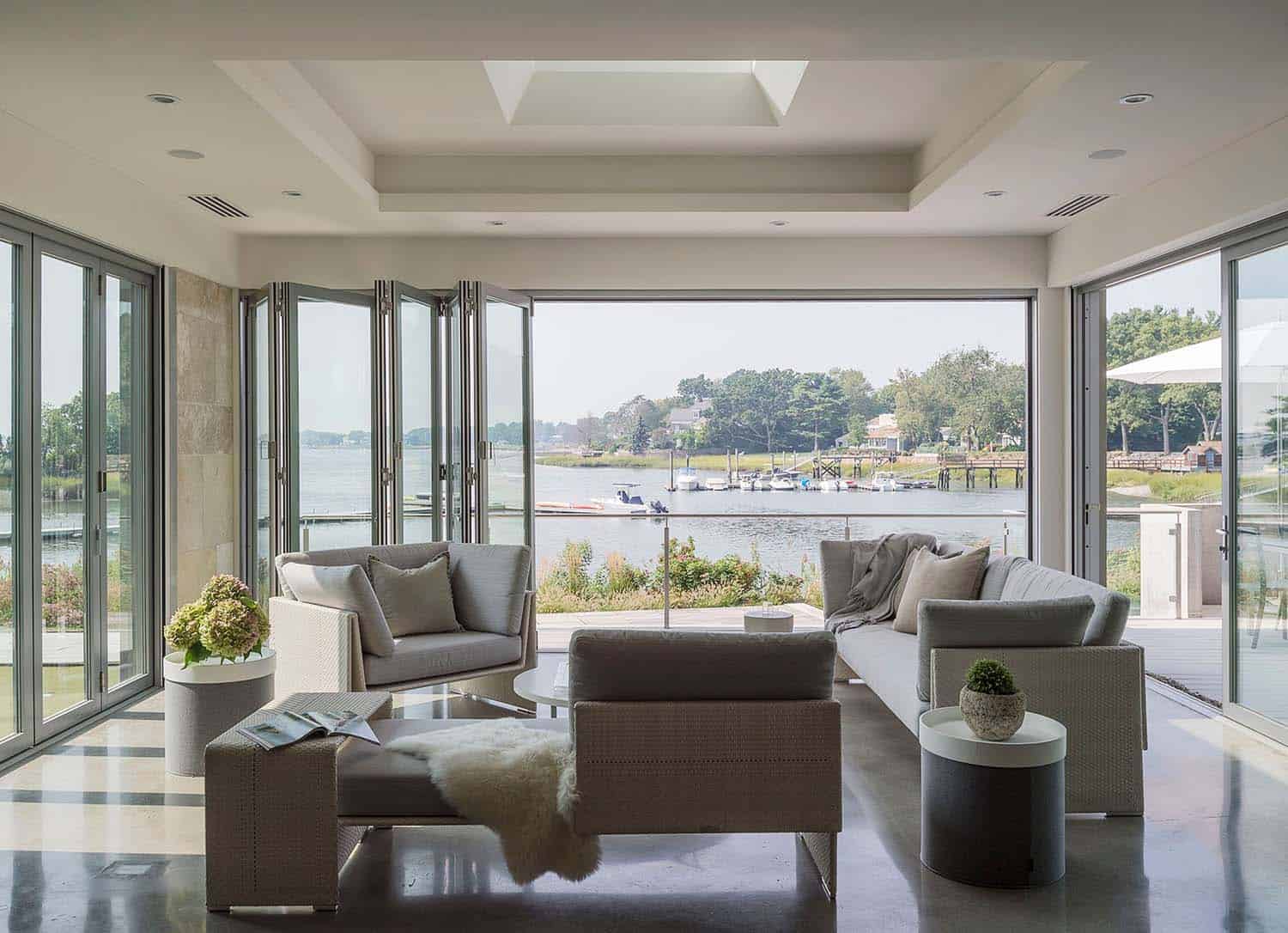 modern sunroom with folding glass doors leading to the outdoor patio and beyond to the waterfront
