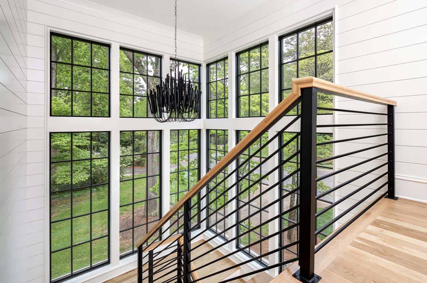 modern staircase with a large window and black chandelier