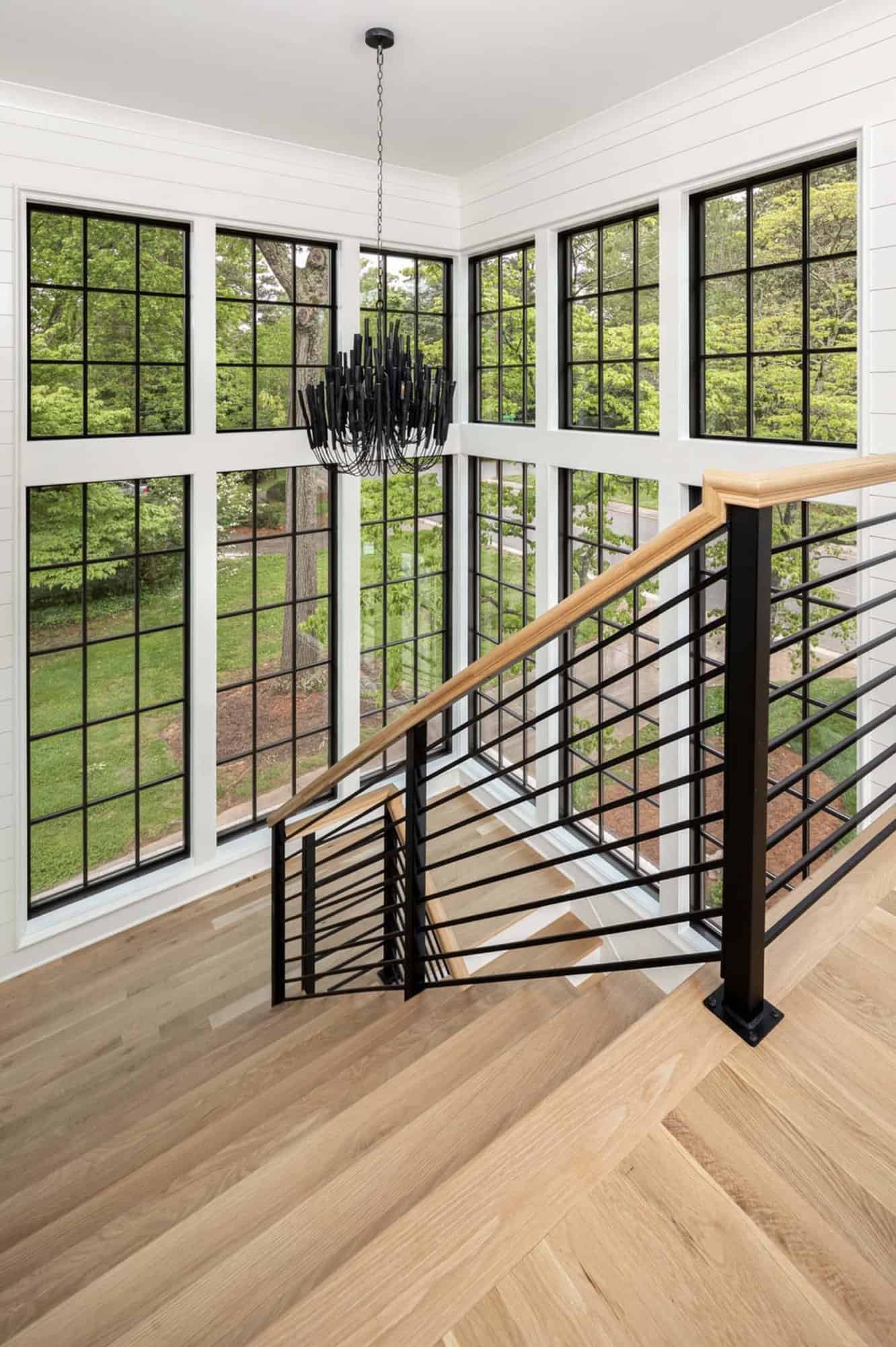 modern staircase with large windows and black chandelier