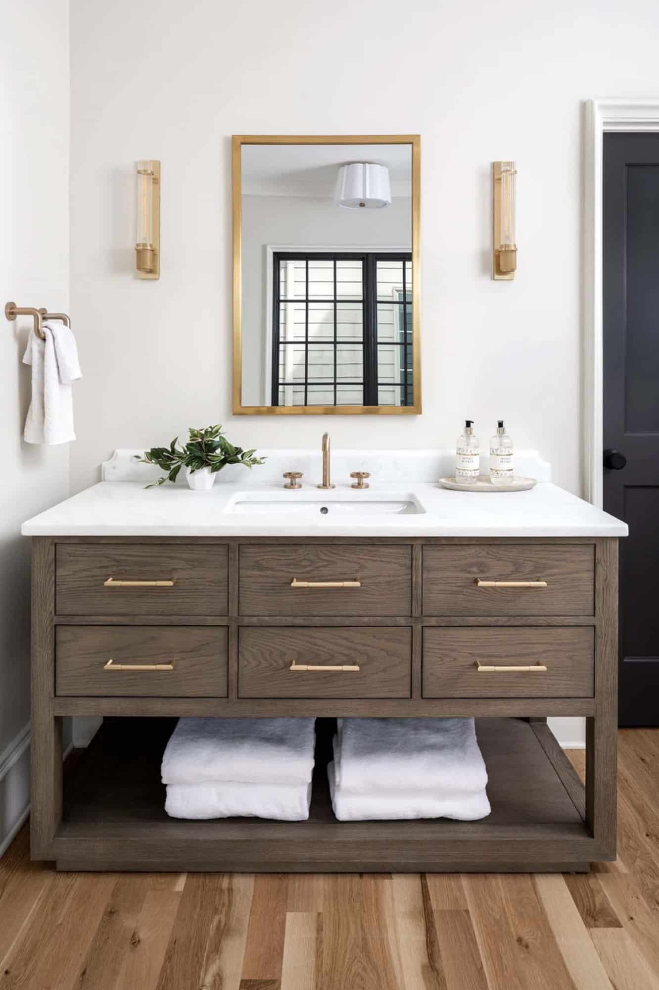 modern bathroom vanity with gold sconces and a mirror