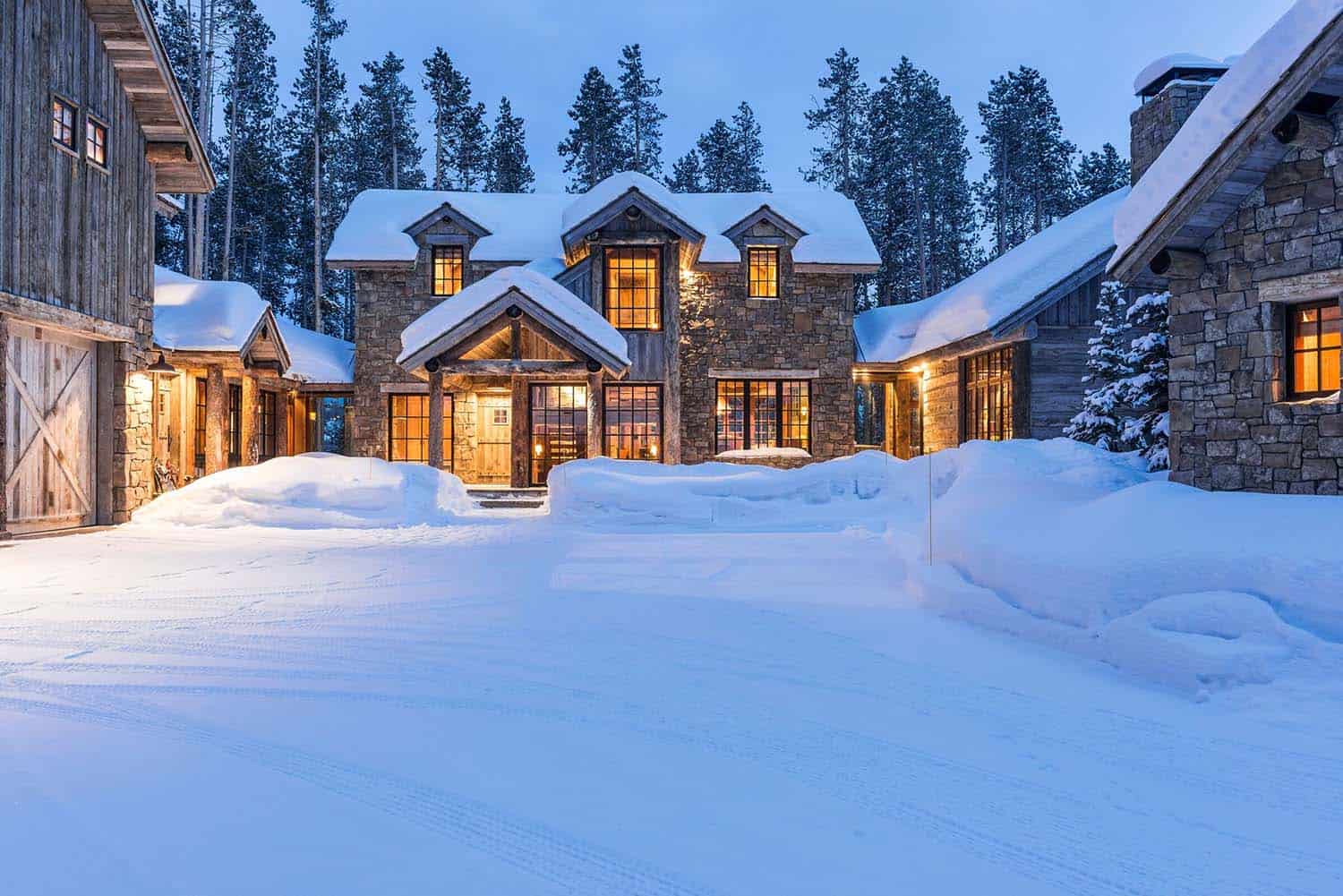 rustic mountain cabin in the woods surrounded by snow at dusk
