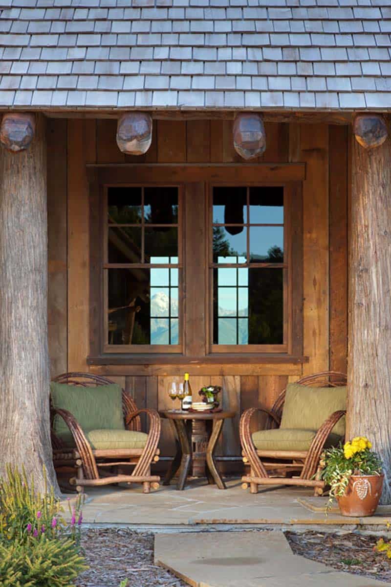 rustic mountain house exterior covered porch with two chairs and a table