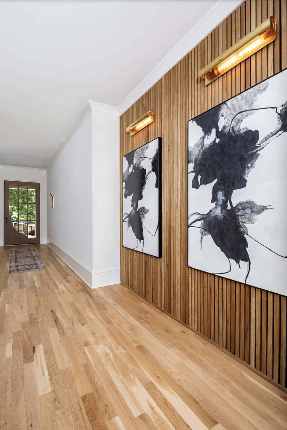 transitional style hallway with a wood feature wall and black and white art