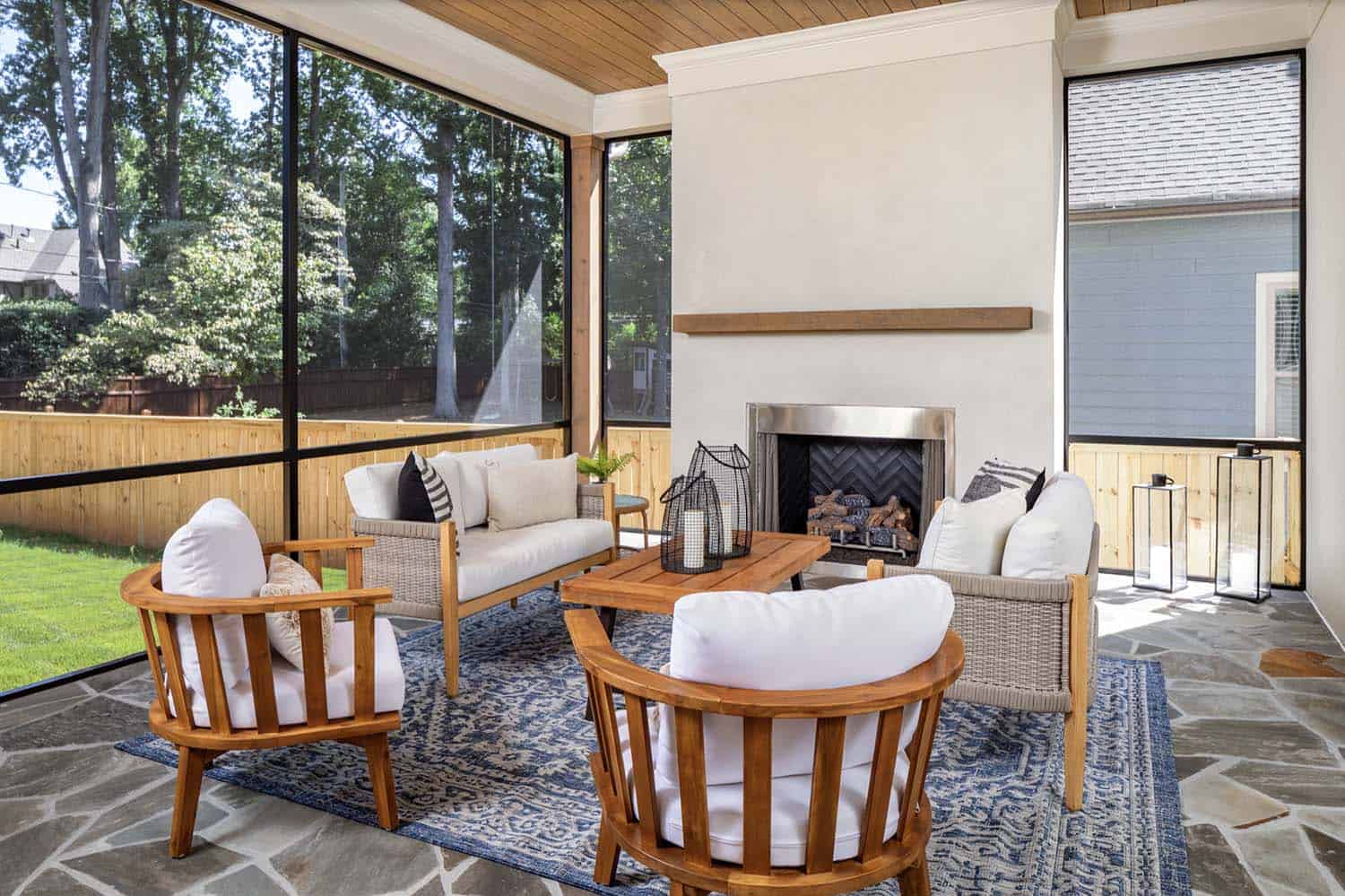 transitional style screened porch with a fireplace and outdoor furniture