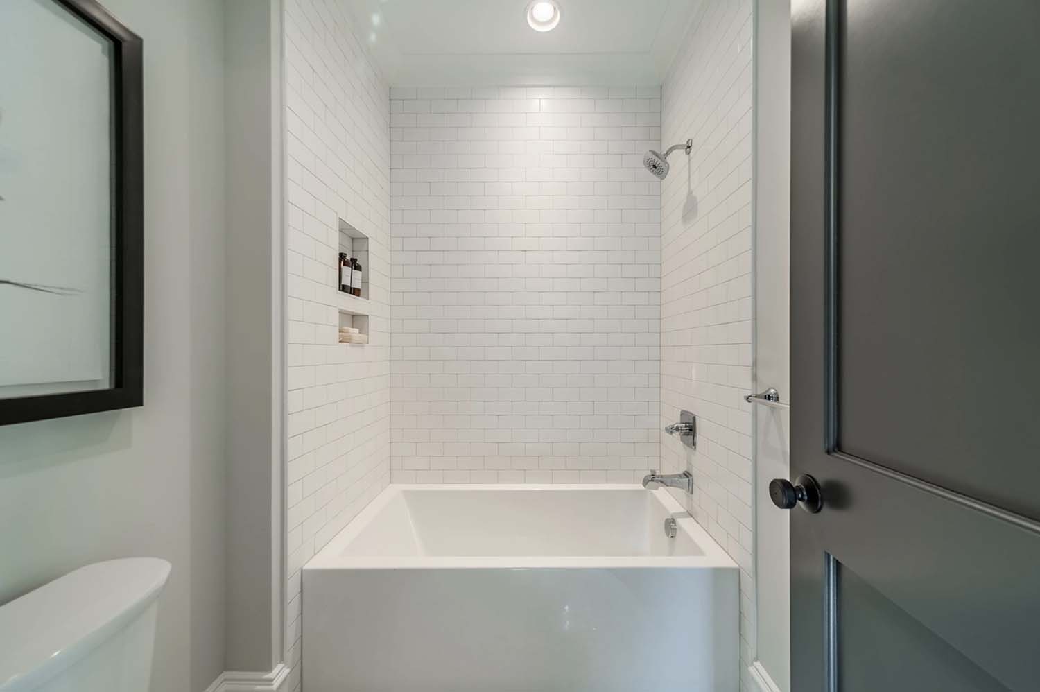 transitional style bathroom tub with white subway tile walls