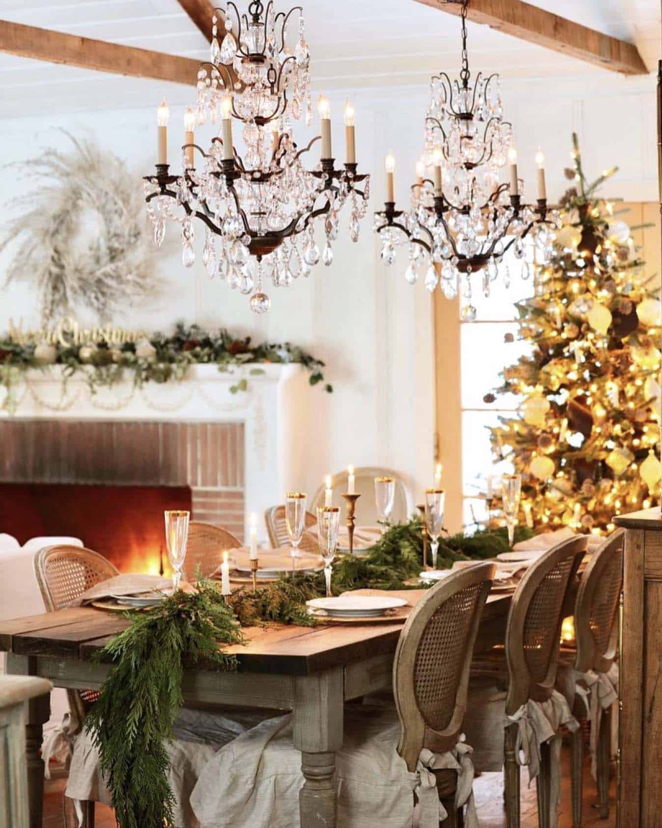 dining table decorated with fresh greens and candles with a christmas tree in the background