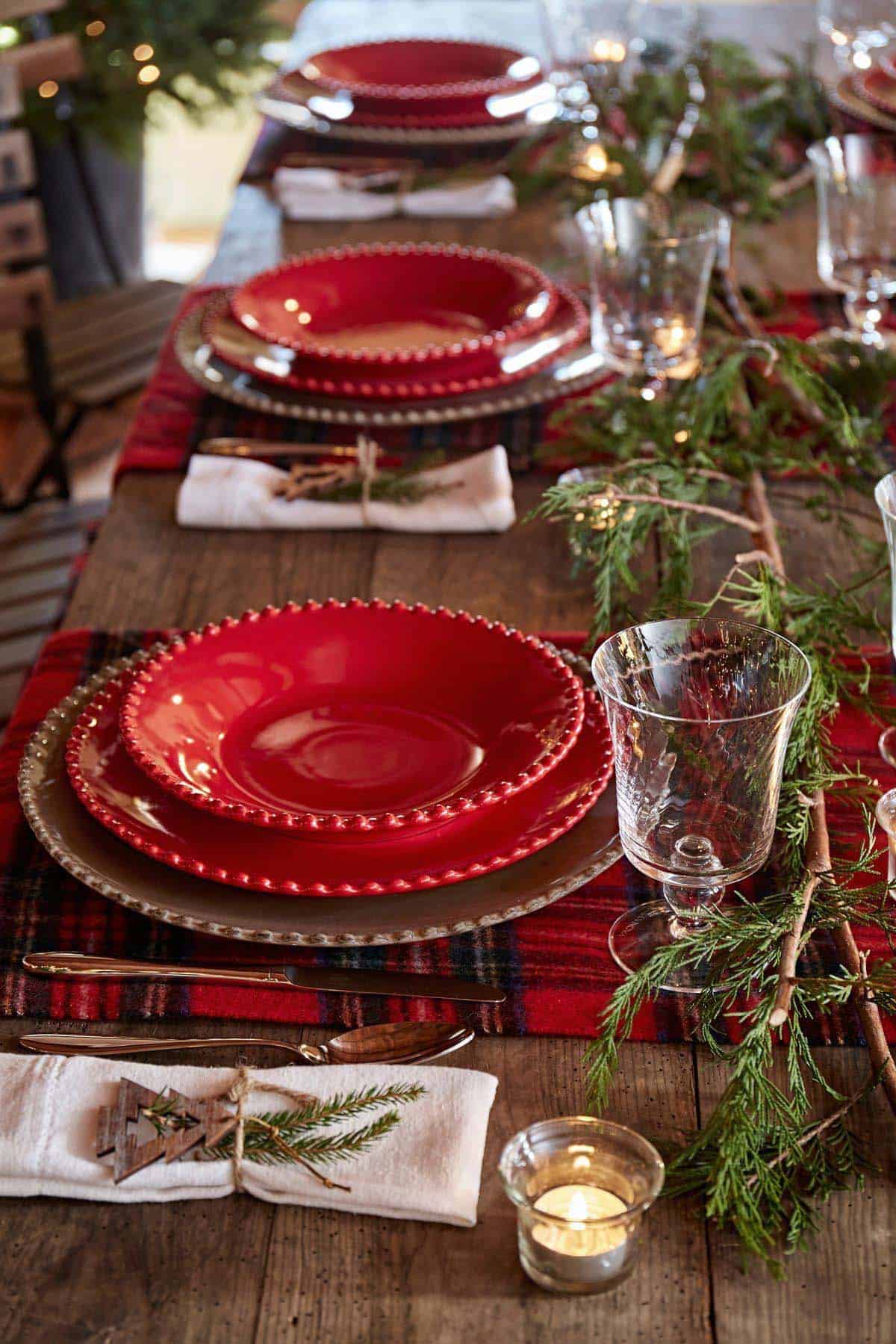 dining table with red christmas dishes and classic tartan table runner