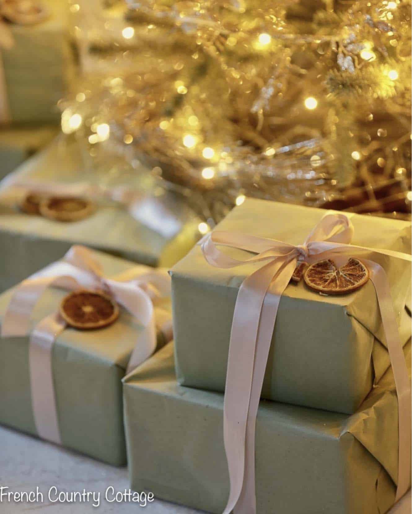 pale green christmas gift wrap with ribbons and dried oranges