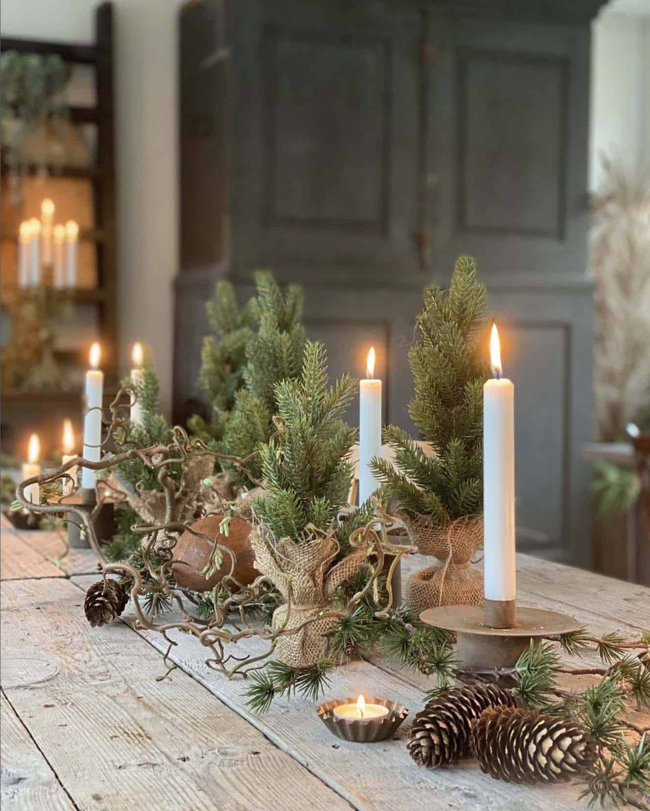 christmas decorated dining table with a centerpiece of small trees and candles