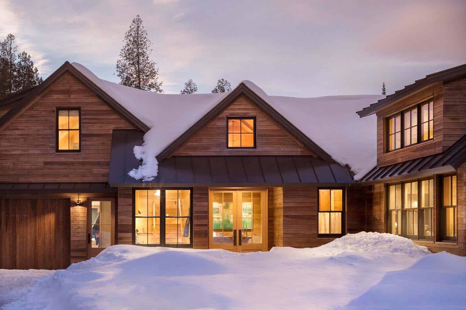 modern rustic mountain home exterior at dusk with snow