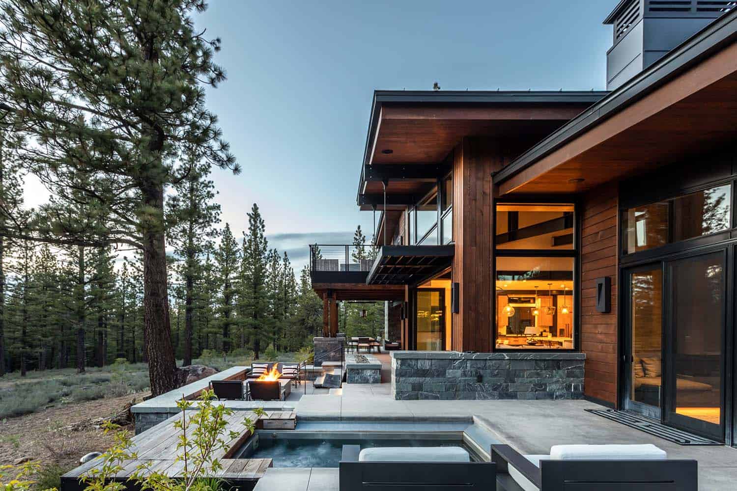 modern mountain home exterior with a large patio and fire pit