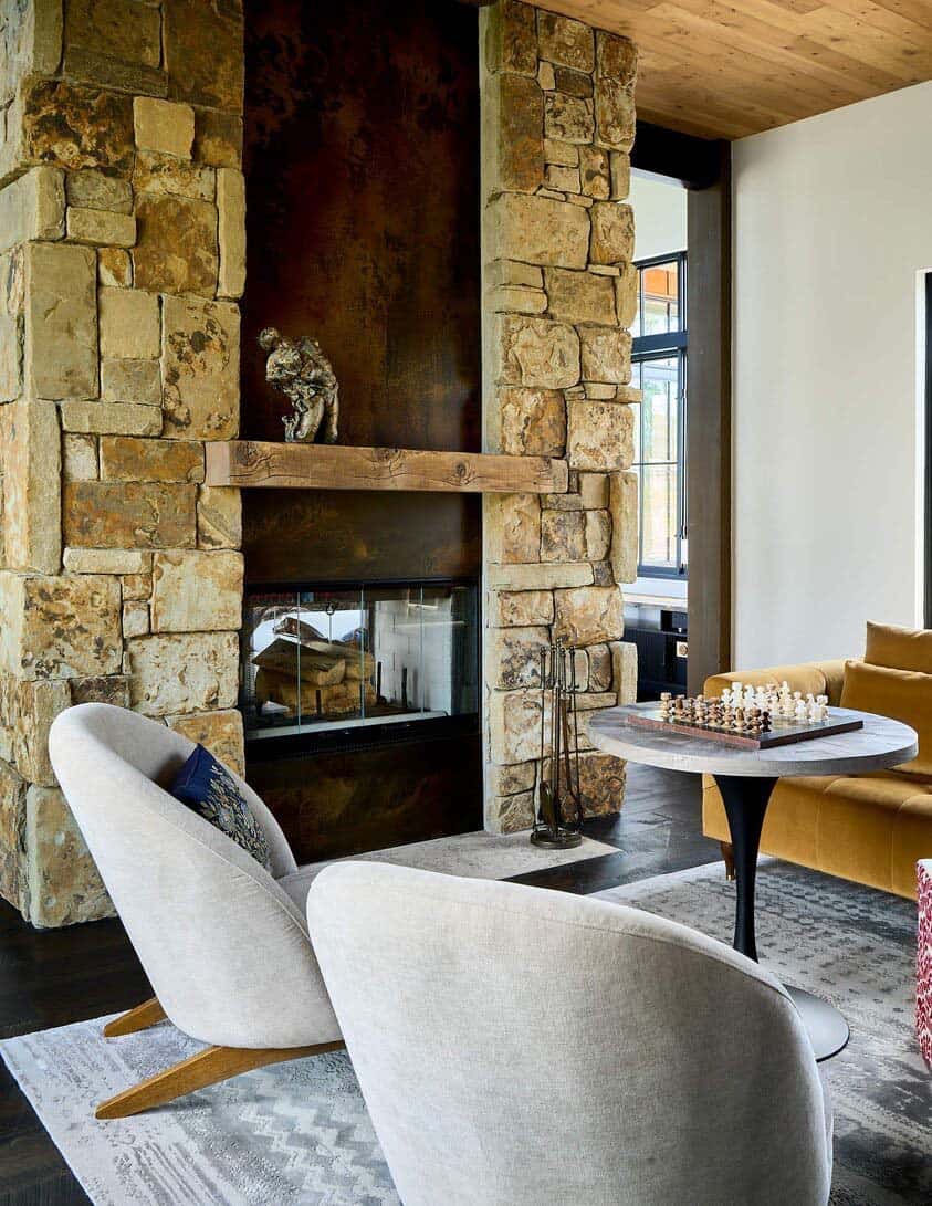 rustic modern home library with a stone clad dual-sided fireplace