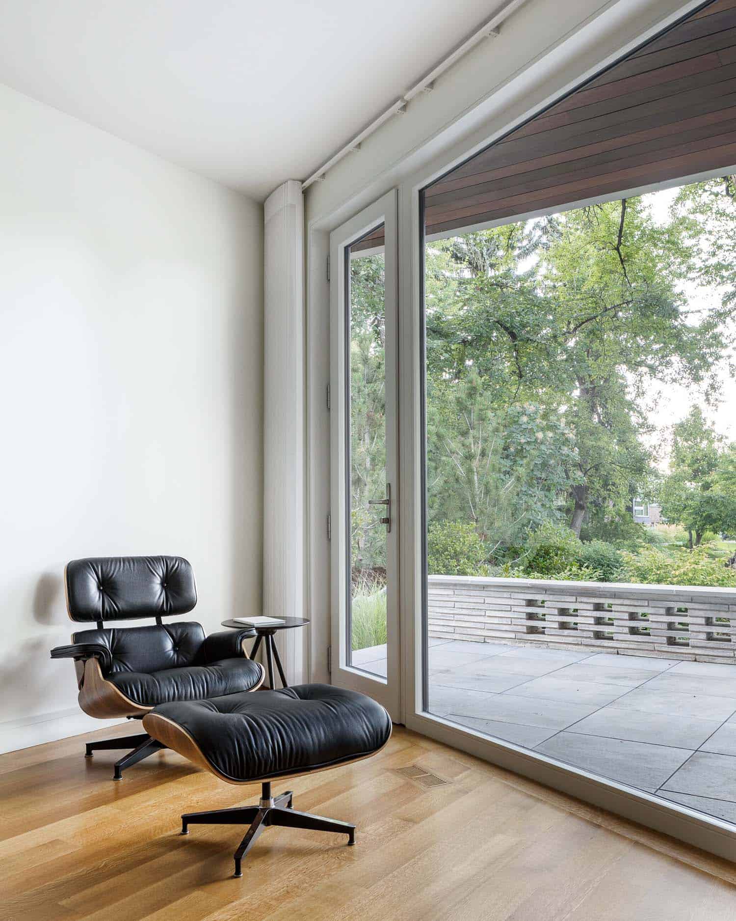 modern Eames chair and ottoman in front of a sliding glass door leading out to a private patio