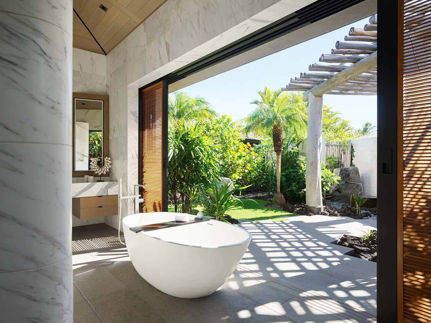 modern coastal style bathroom with a freestanding tub overlooking the backyard