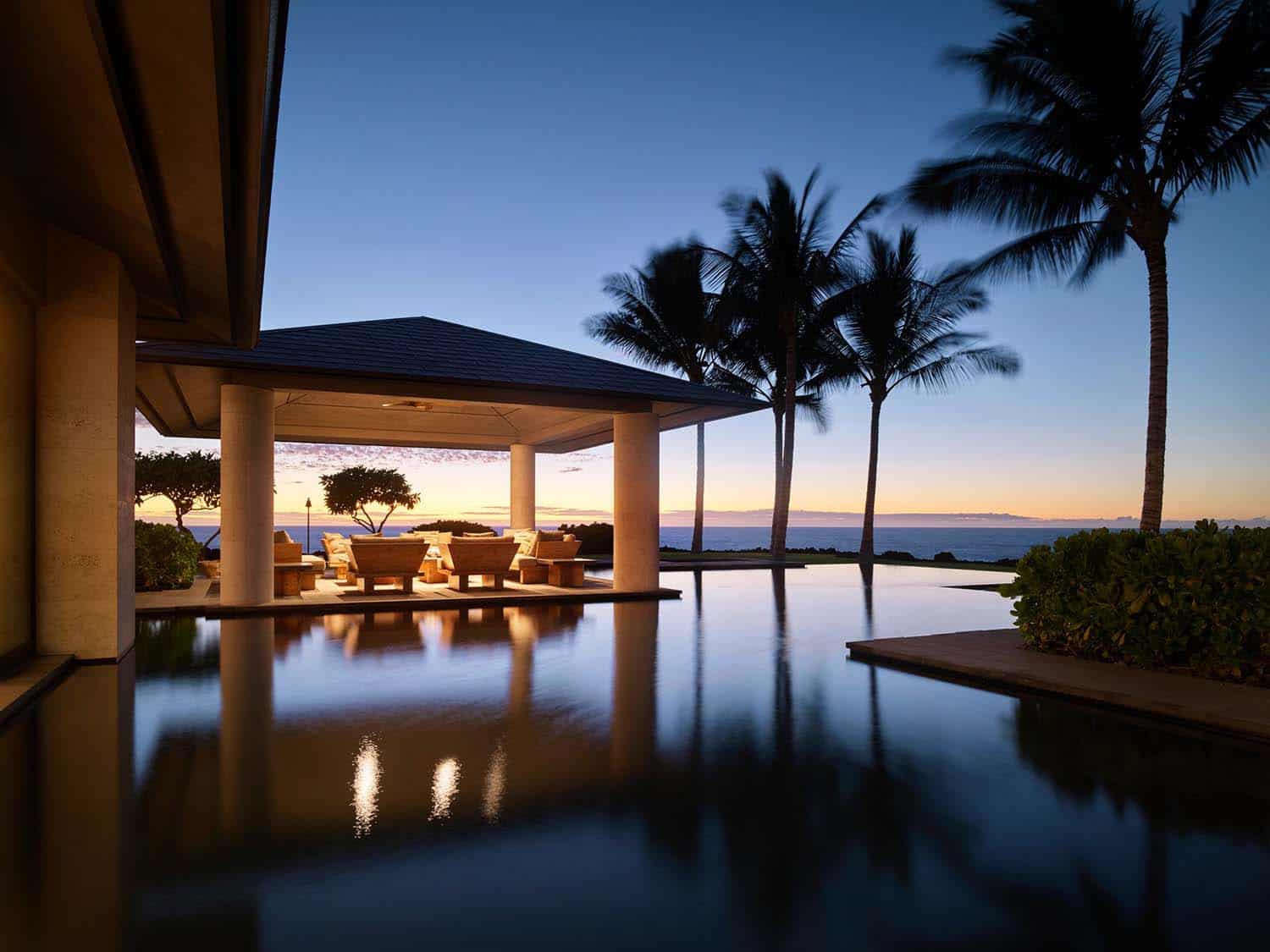 modern coastal style outdoor dining pavilion and swimming pool at dusk