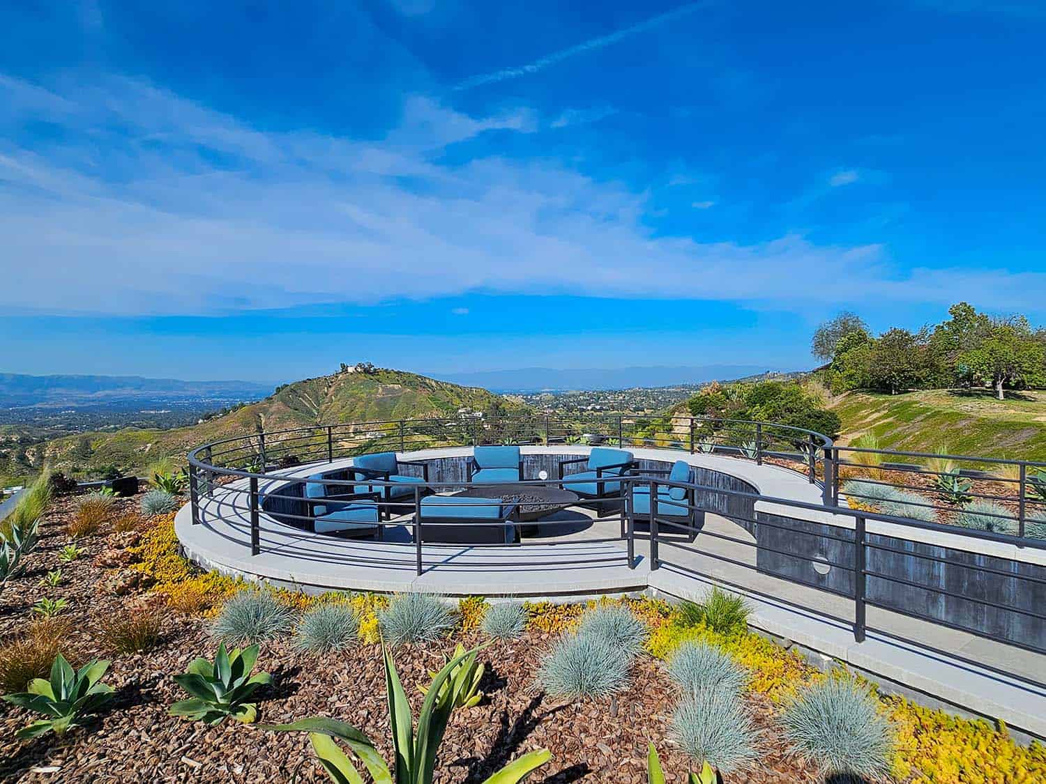 modern hilltop house exterior with a circular patio and a fire pit