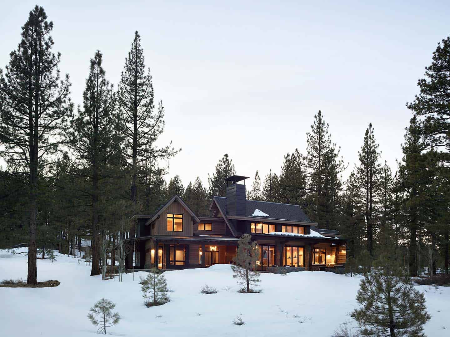 modern mountain home exterior with snow at dusk