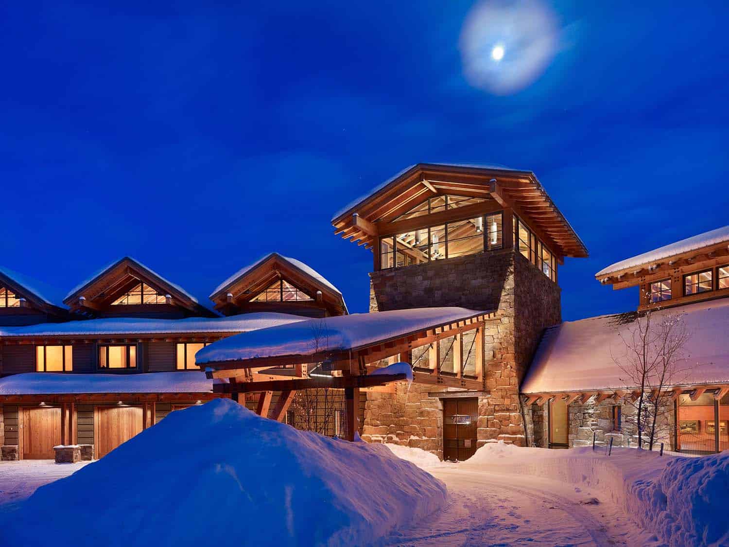 modern rustic mountain home exterior with snow at dusk