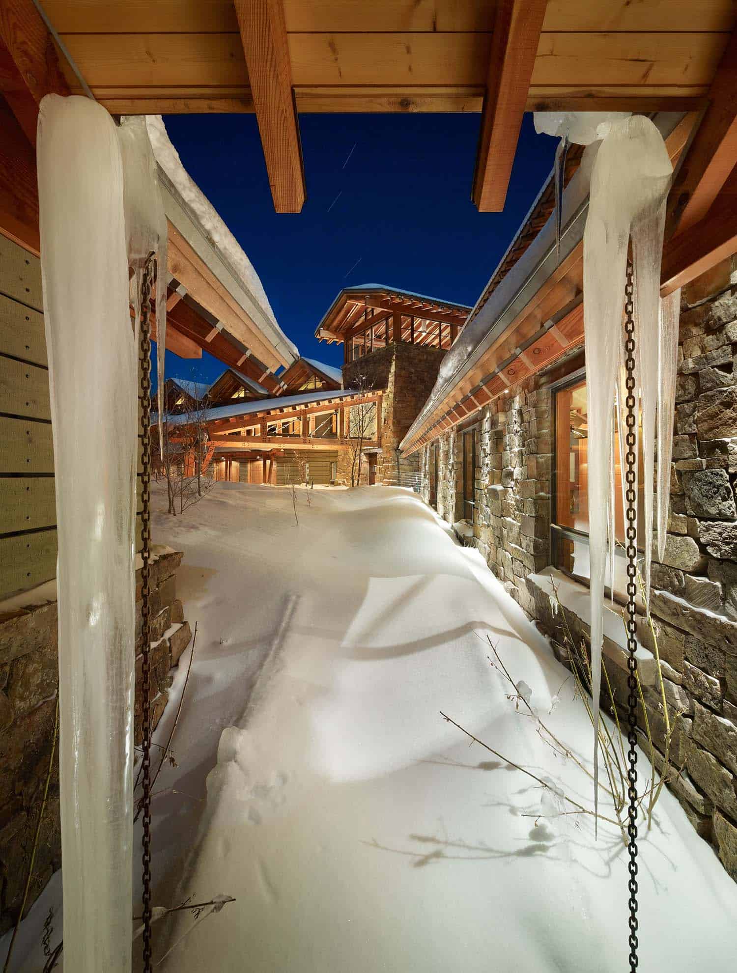 modern rustic mountain home exterior with snow at dusk