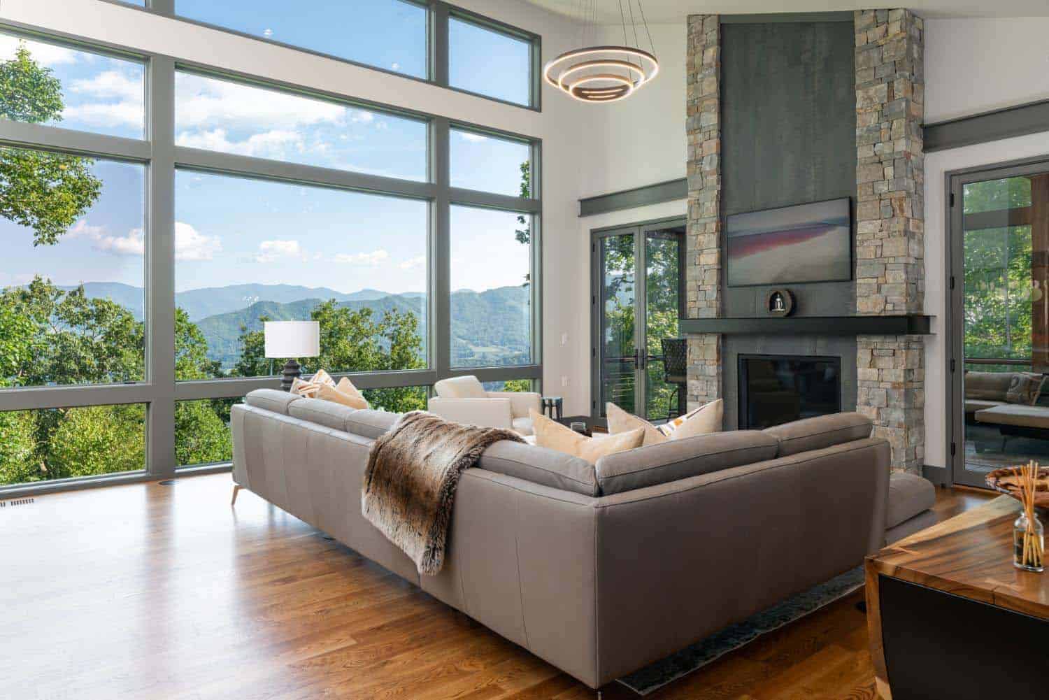 modern living room with a fireplace and large window framing mountain views