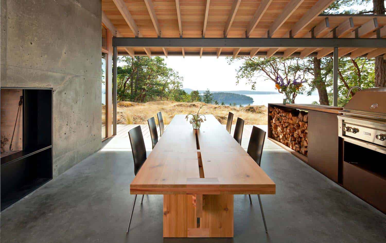 modern covered porch with dining furniture and an outdoor kitchen looking out to nature