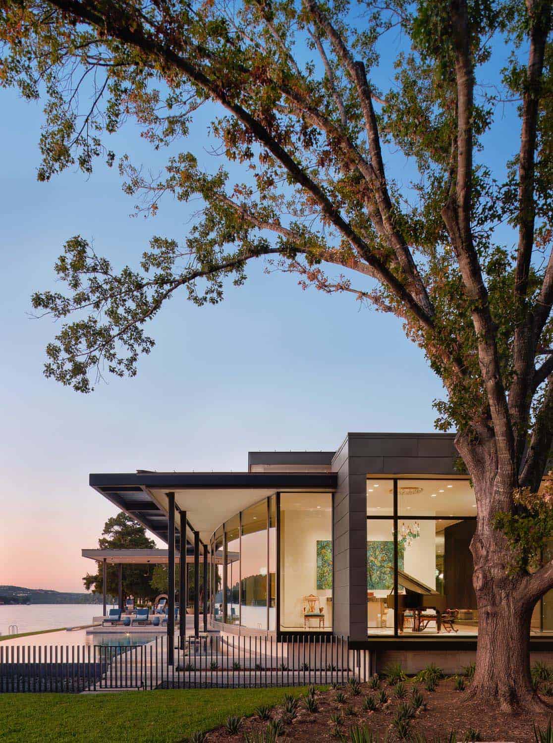 modern lake house exterior with a pool at dusk