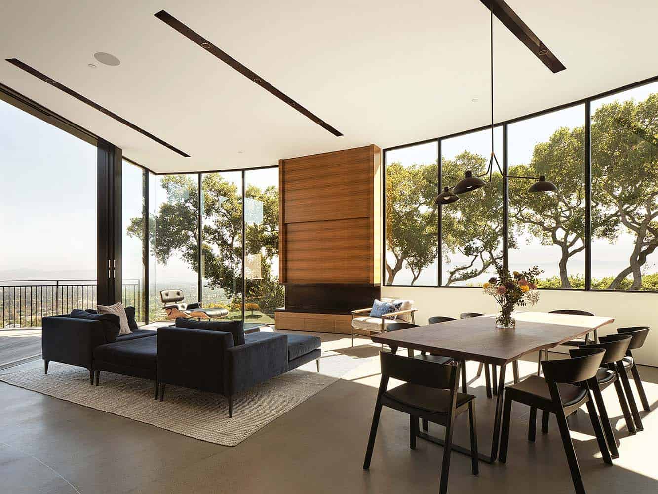 modern dining and living room with a fireplace and large windows