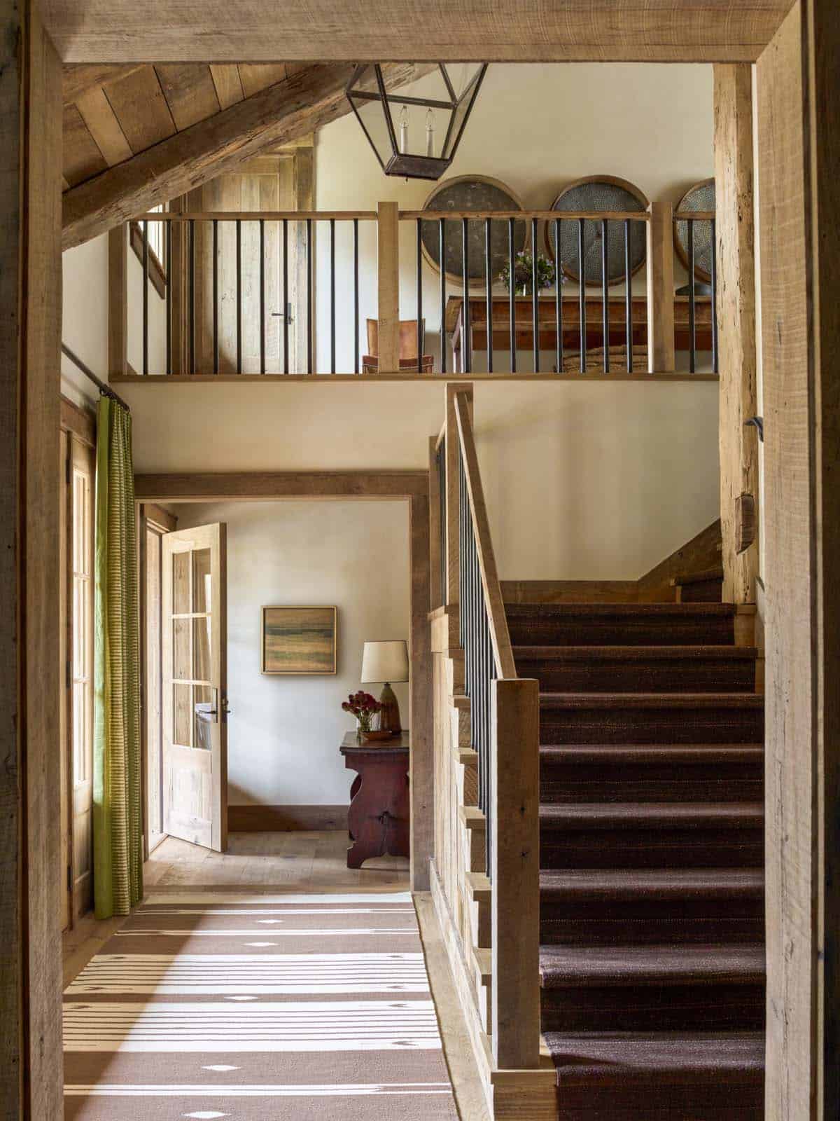 modern rustic staircase and hallway leading to the front entry door