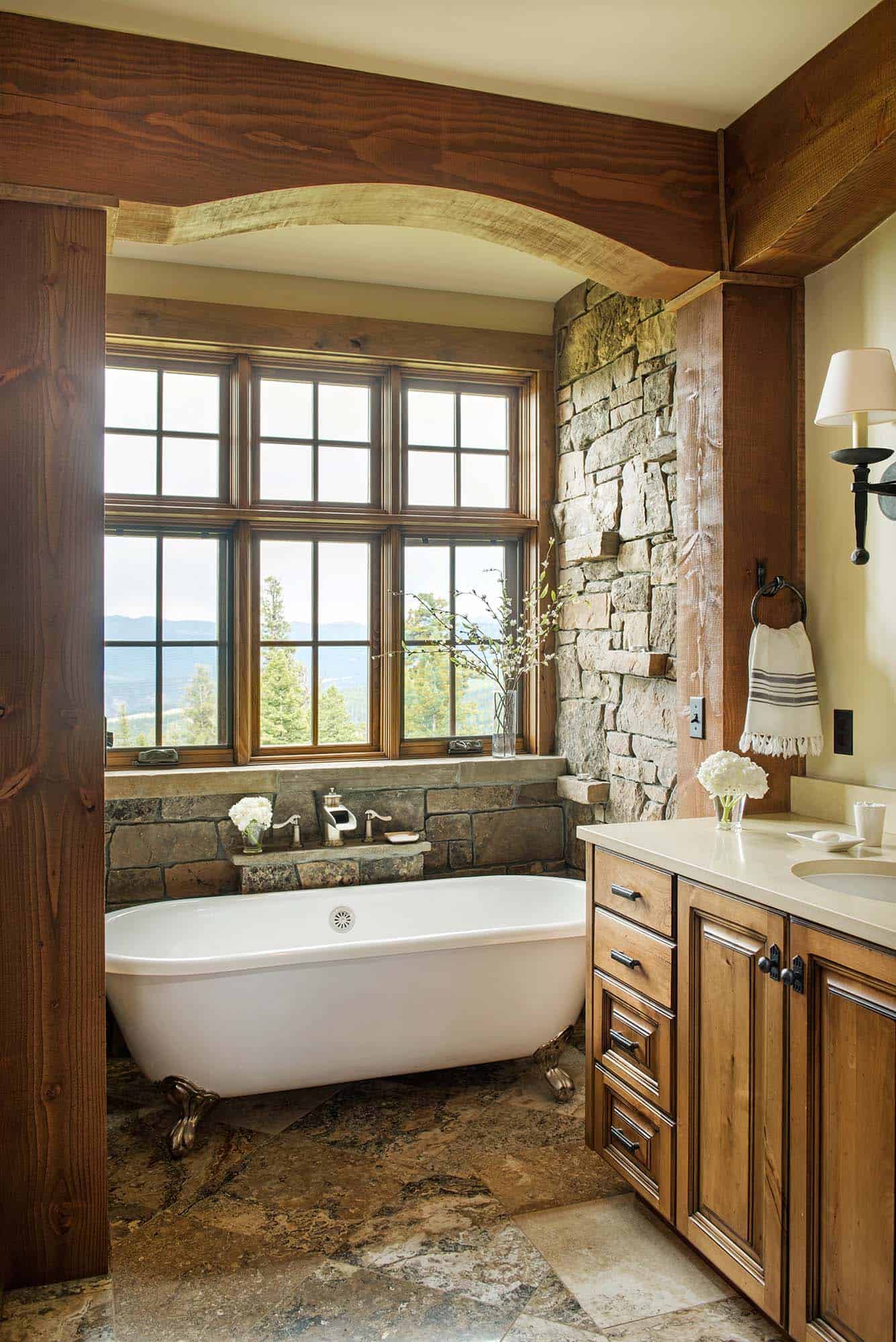 rustic bathroom with a vanity and freestanding tub in front of windows