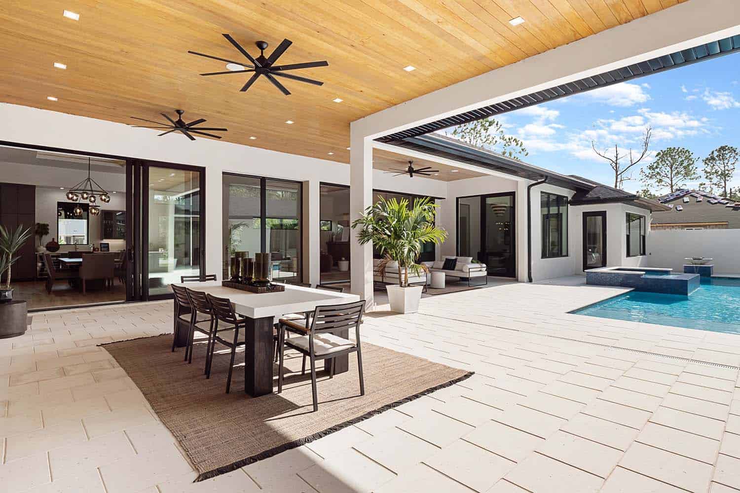 modern tropical model home exterior with a covered patio and outdoor furniture