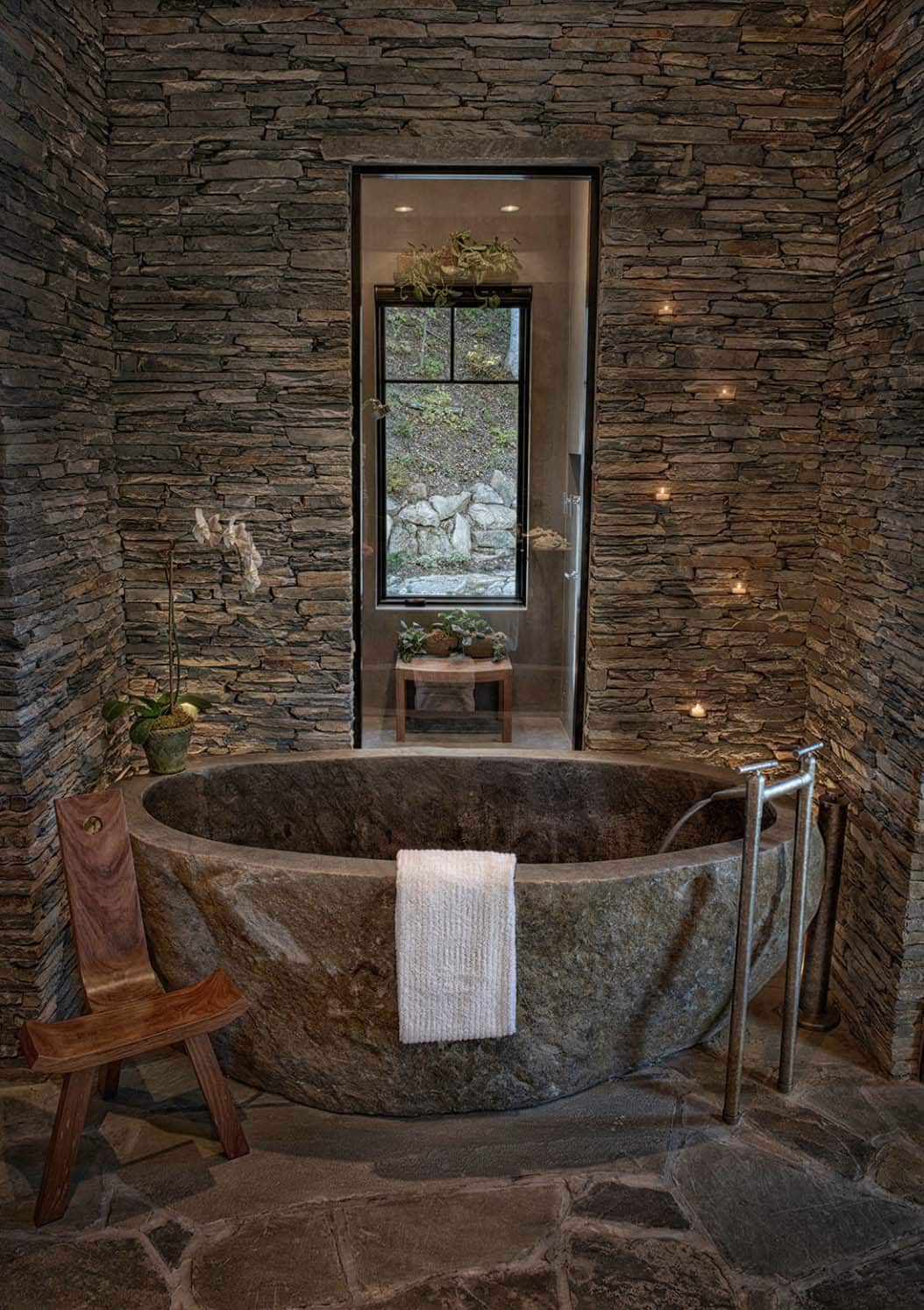 romantic rustic bathroom with a stone tub and stone walls