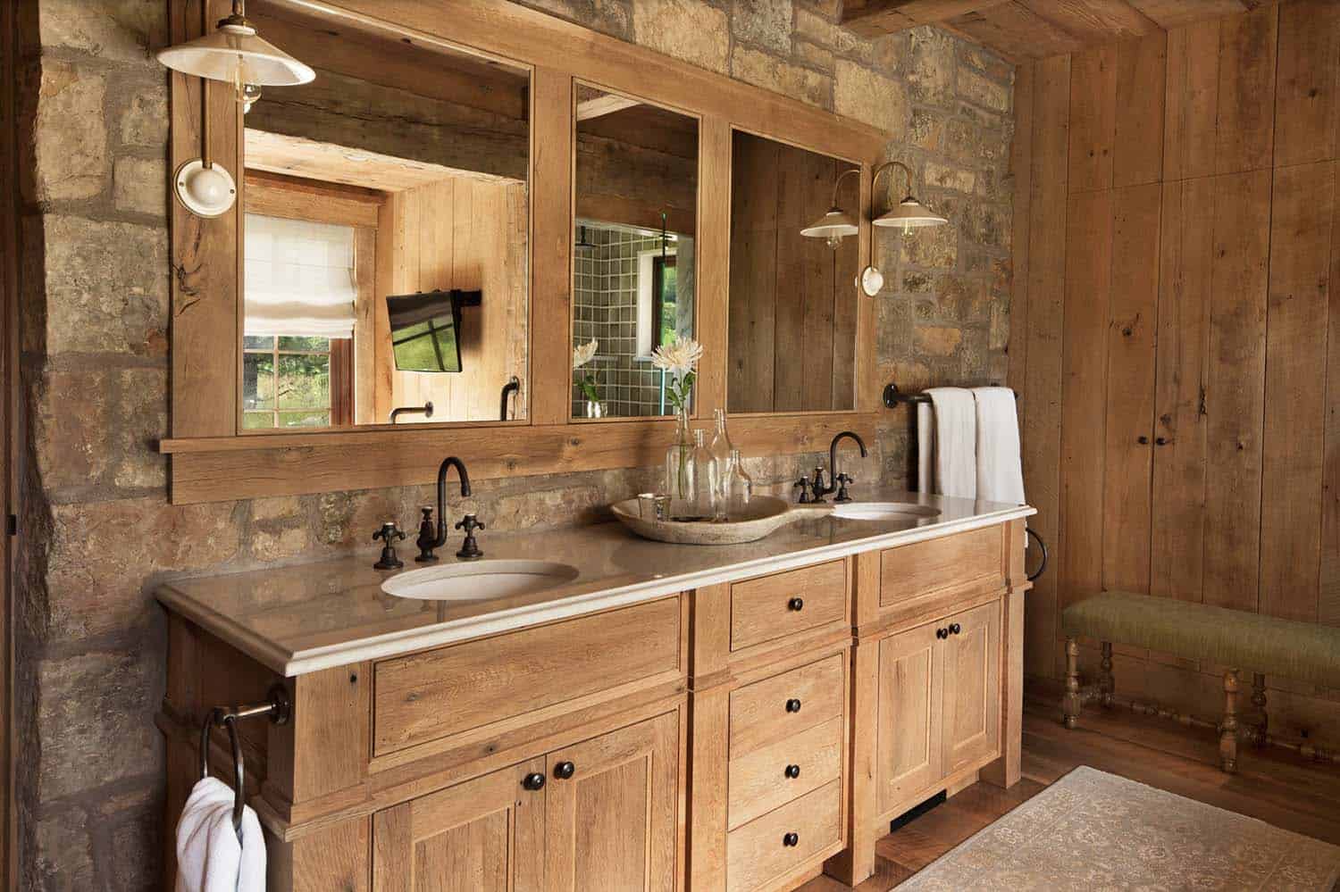 rustic bathroom with a dual sink vanity and stone wall