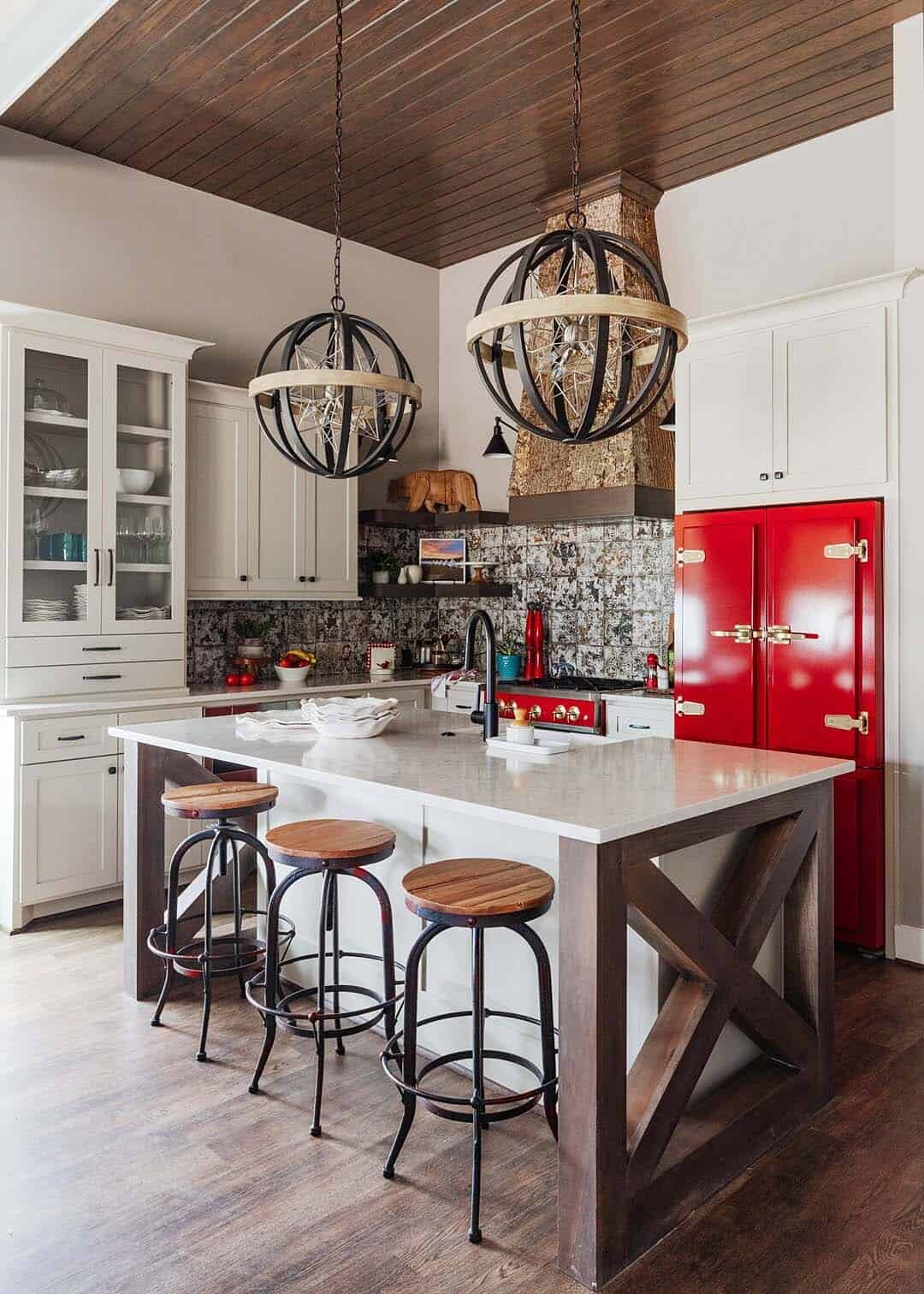 rustic kitchen with a red retro fridge and large pendant lights over the island