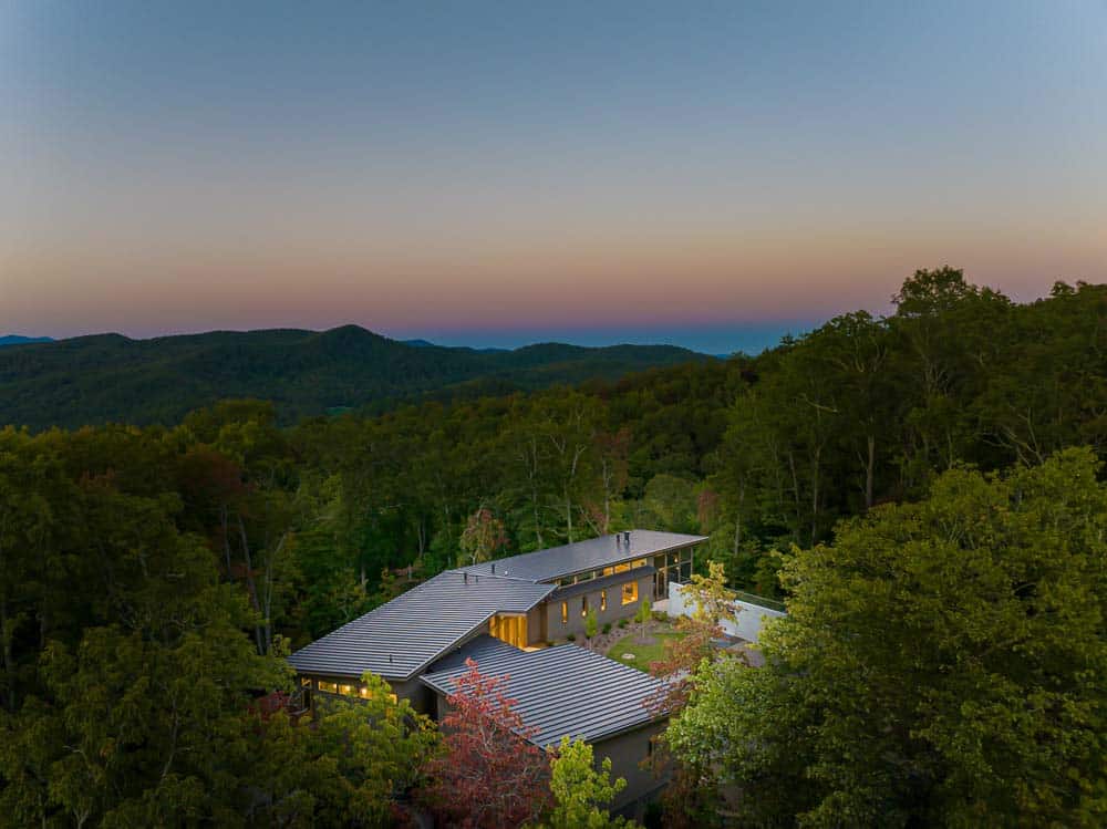 modern mountainside home aerial view at dusk