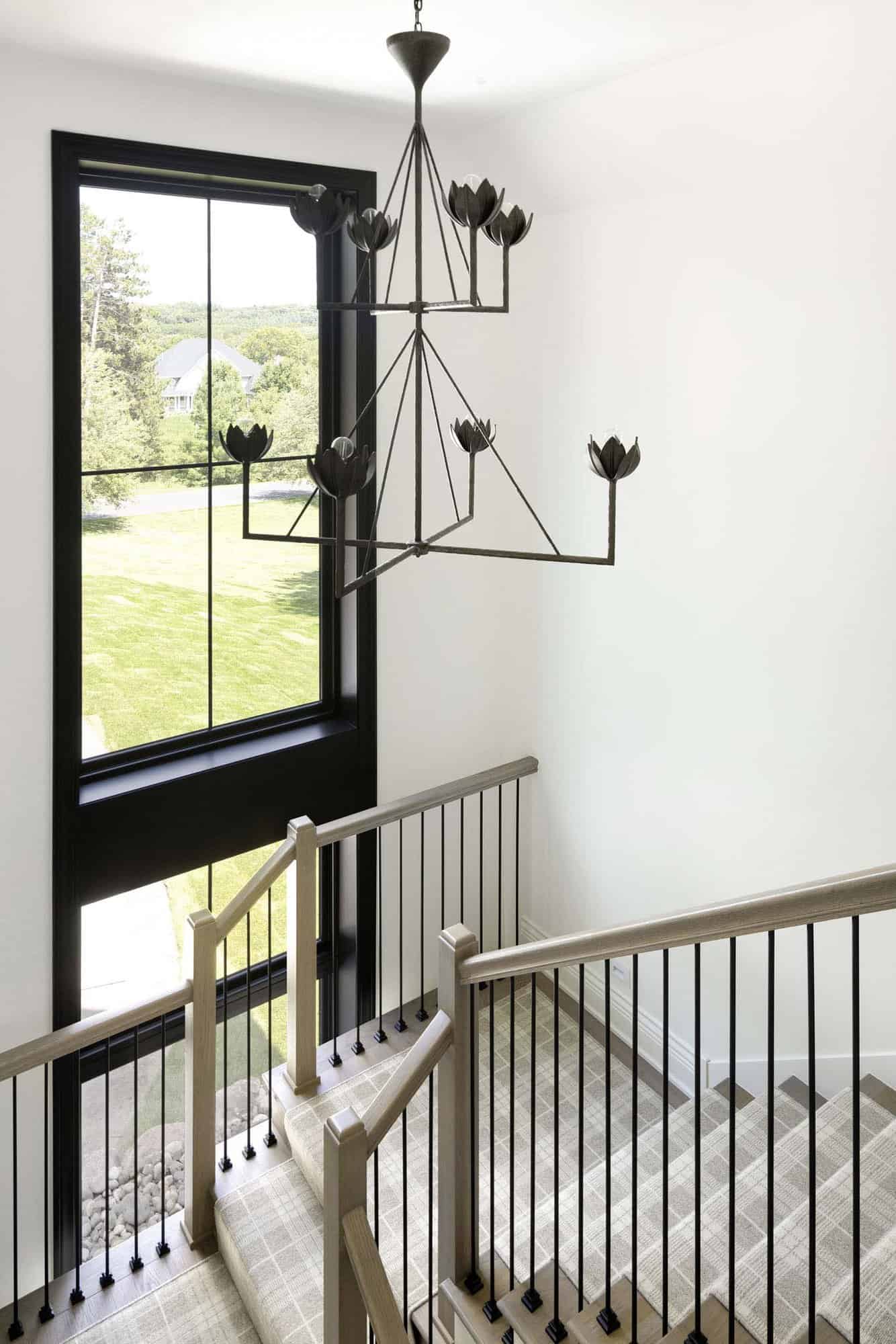 modern traditional staircase with a large window and chandelier