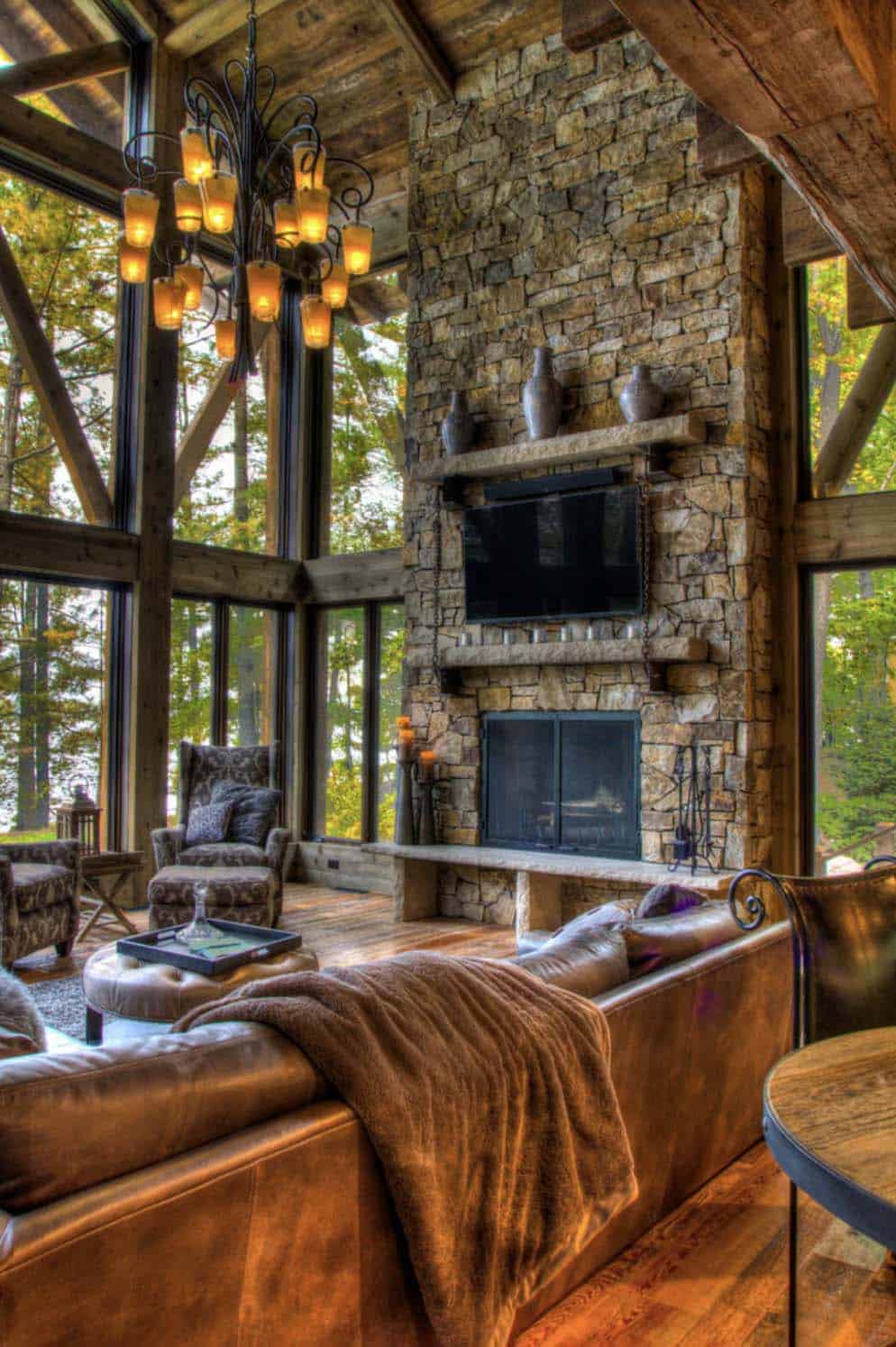 rustic living room with a floor-to-ceiling stone fireplace and large windows
