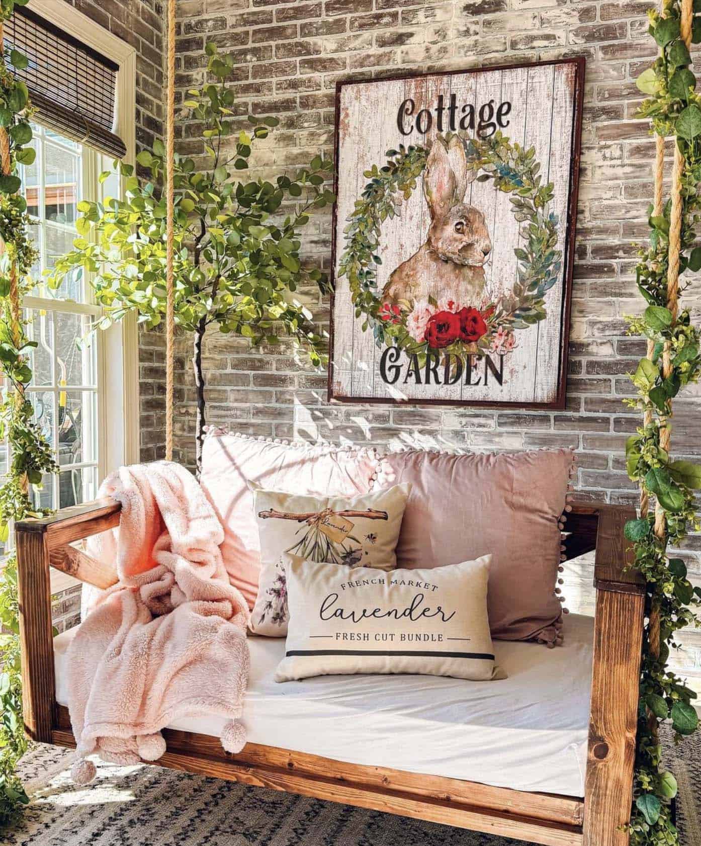 front porch with a porch swing, pillows and a spring sign on the wall