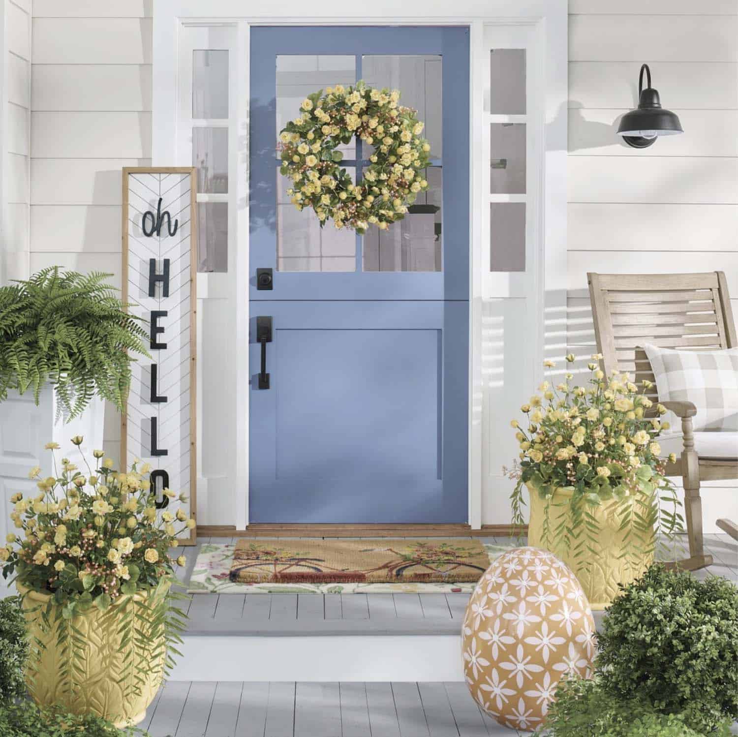 spring front porch decor with a sign, door wreath and potted plants