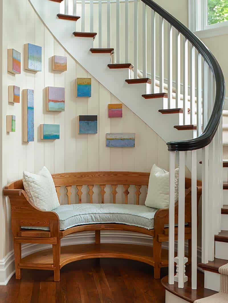 traditional coastal style curved staircase with a bench