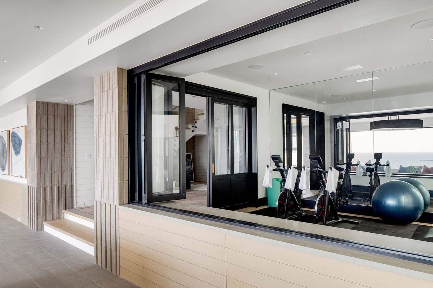 coastal contemporary hallway with a window view into the home gym