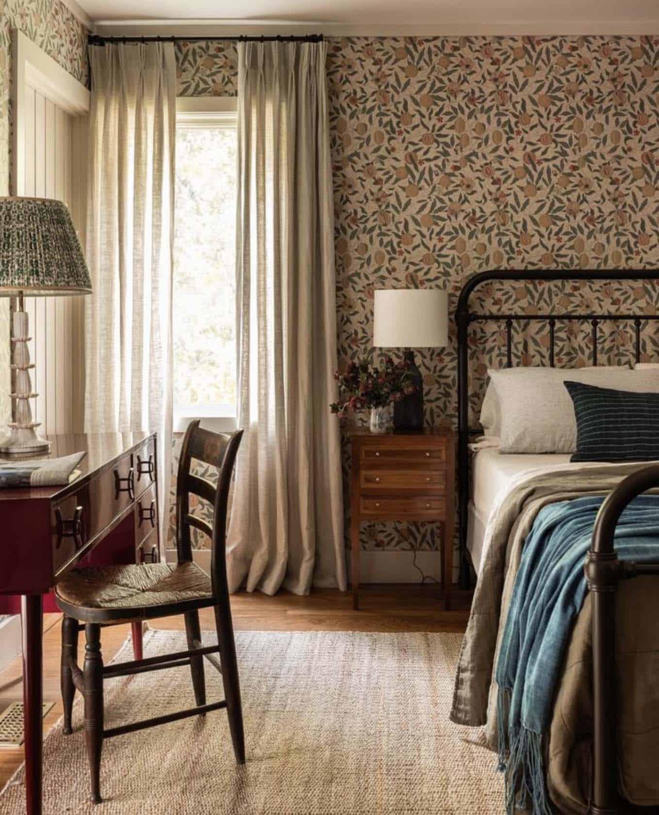 cozy guest bedroom with wallpaper and a desk with a chair