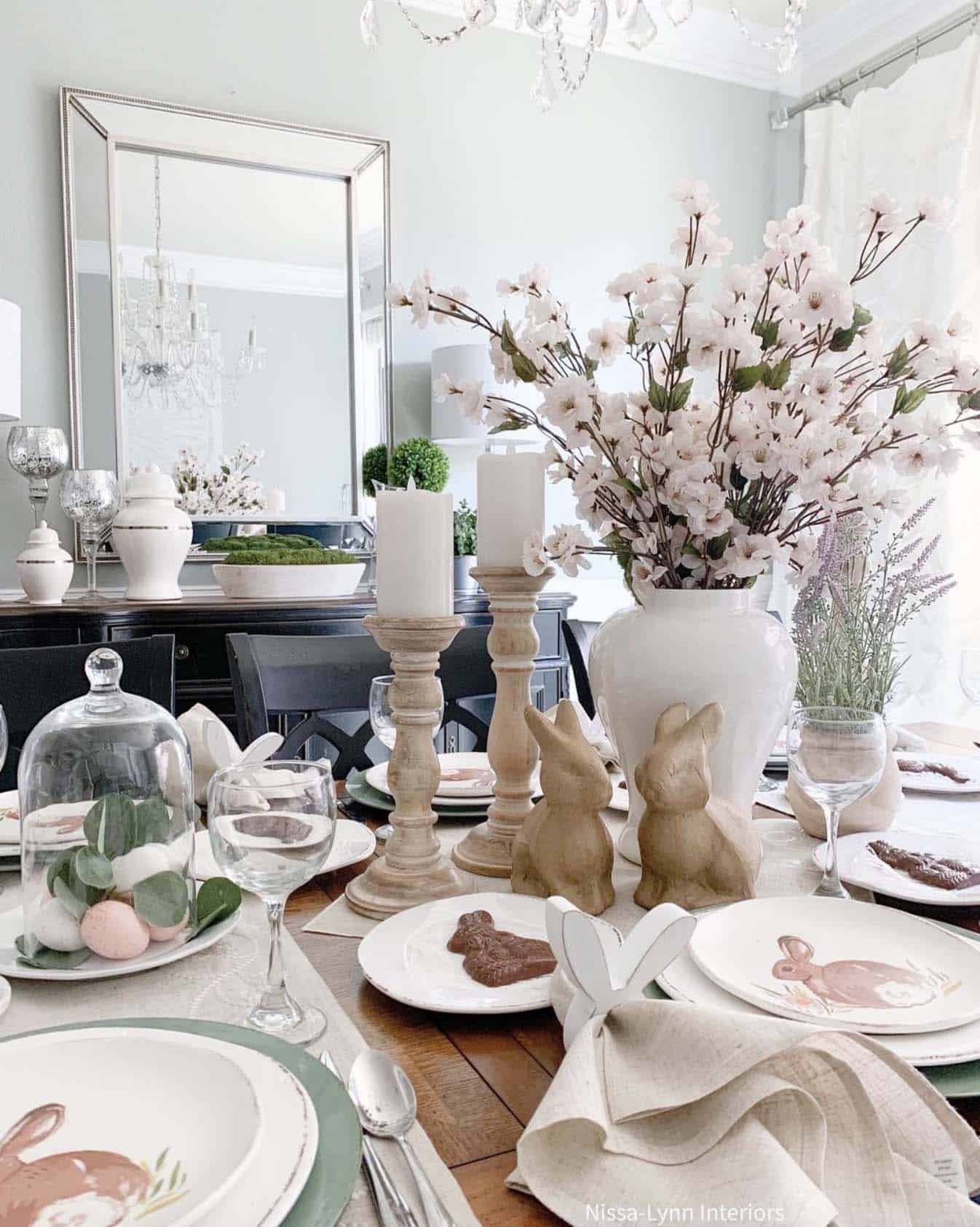 easter table setting with candles, wood bunnies and a vase of faux spring flowers